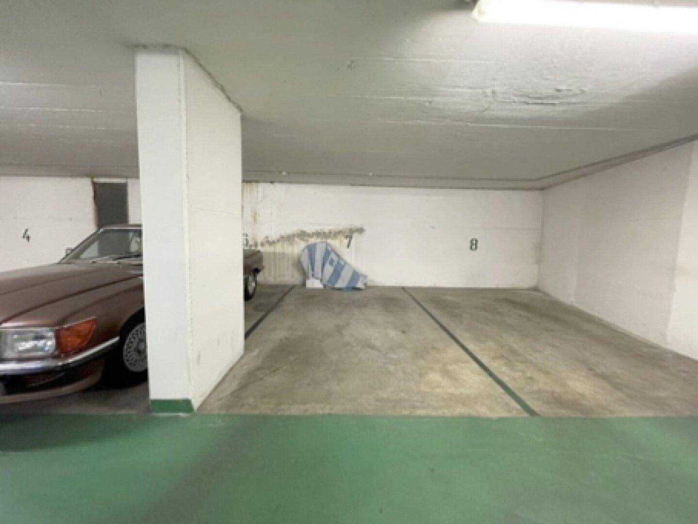 Einzelner Stellplatz in der Tiefgarage mit Betonboden und einer Wand, die Renovierung benötigt.