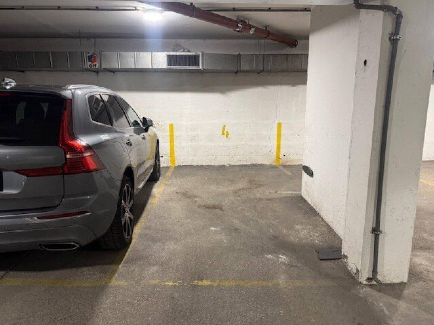 Markierter Stellplatz Nummer 4 in einer gut beleuchteten Tiefgarage mit Betonboden.