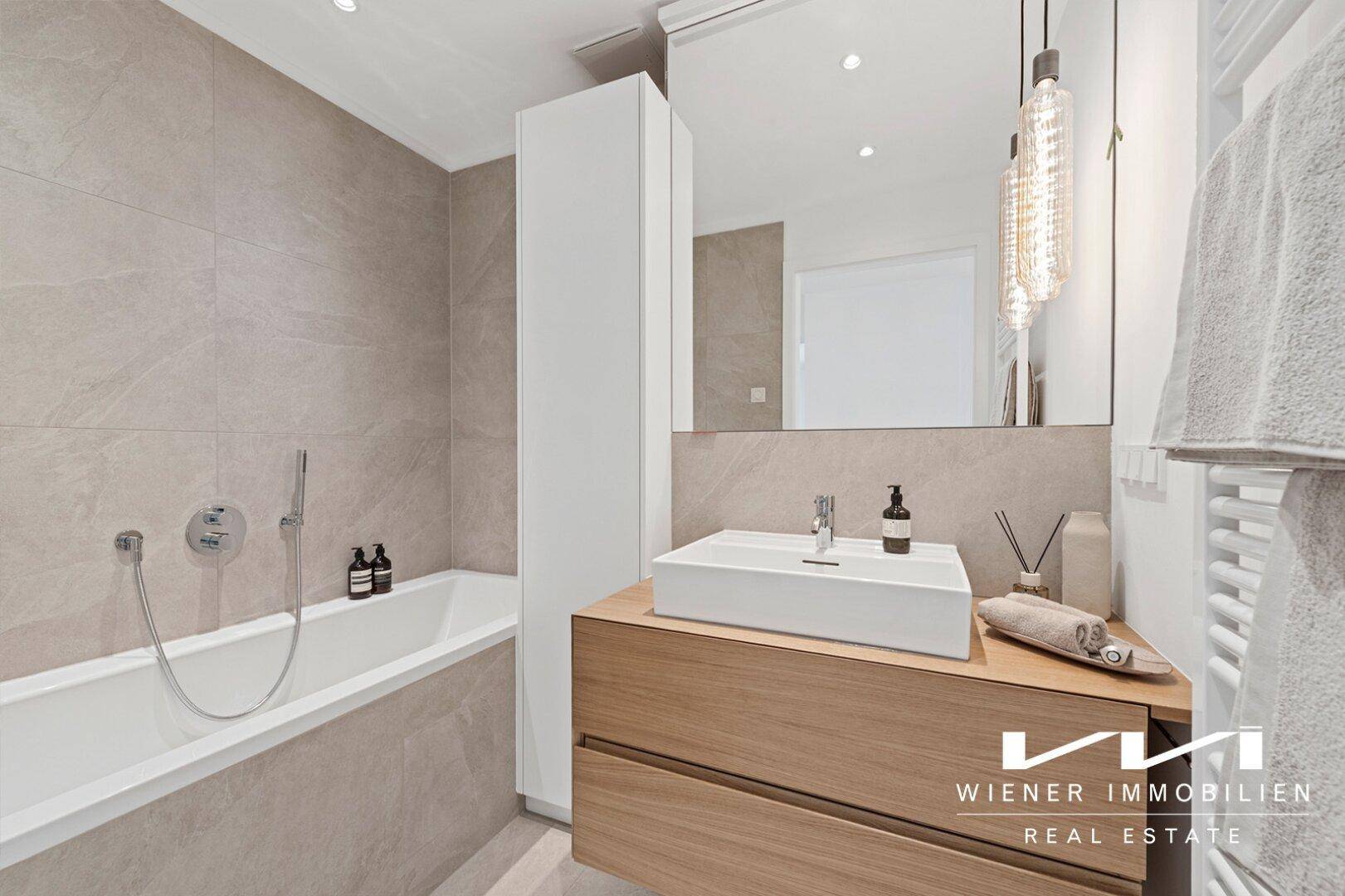 Modernes Badezimmer mit Badewanne, eleganten Fliesen und einem stilvollen Waschtisch mit Holzunterschrank.