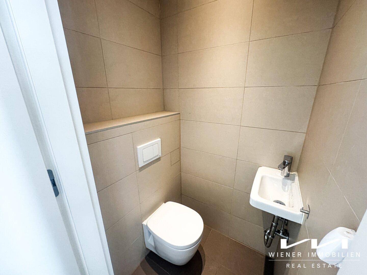 Modernes Gäste-WC mit Wand-WC und kleinem Waschbecken.