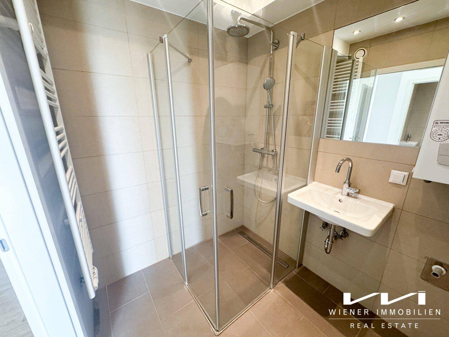 Modernes Badezimmer mit Duschkabine, Waschbecken und beheiztem Handtuchhalter.