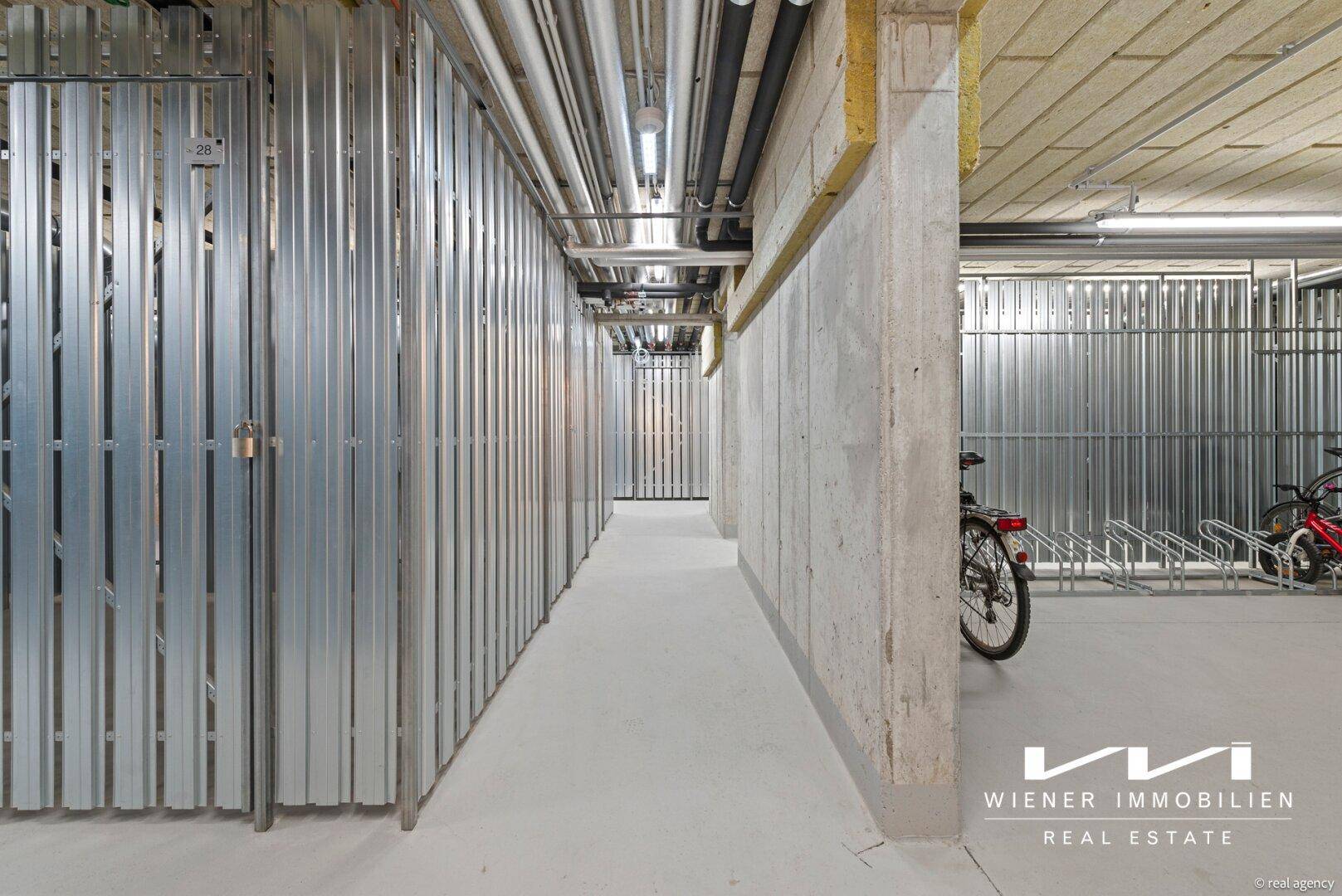 Fahrradraum und Abstellbereiche im Untergeschoss mit Metallabtrennungen und Beleuchtung.