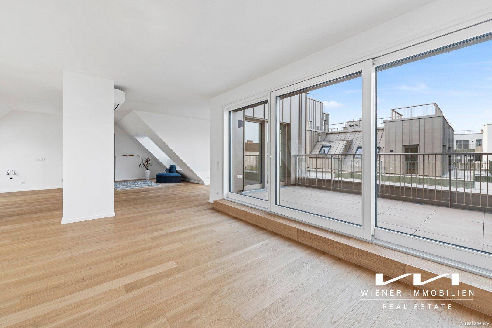 Heller Wohnraum mit Holzboden und Zugang zu einer großen Terrasse mit Stadtblick.
