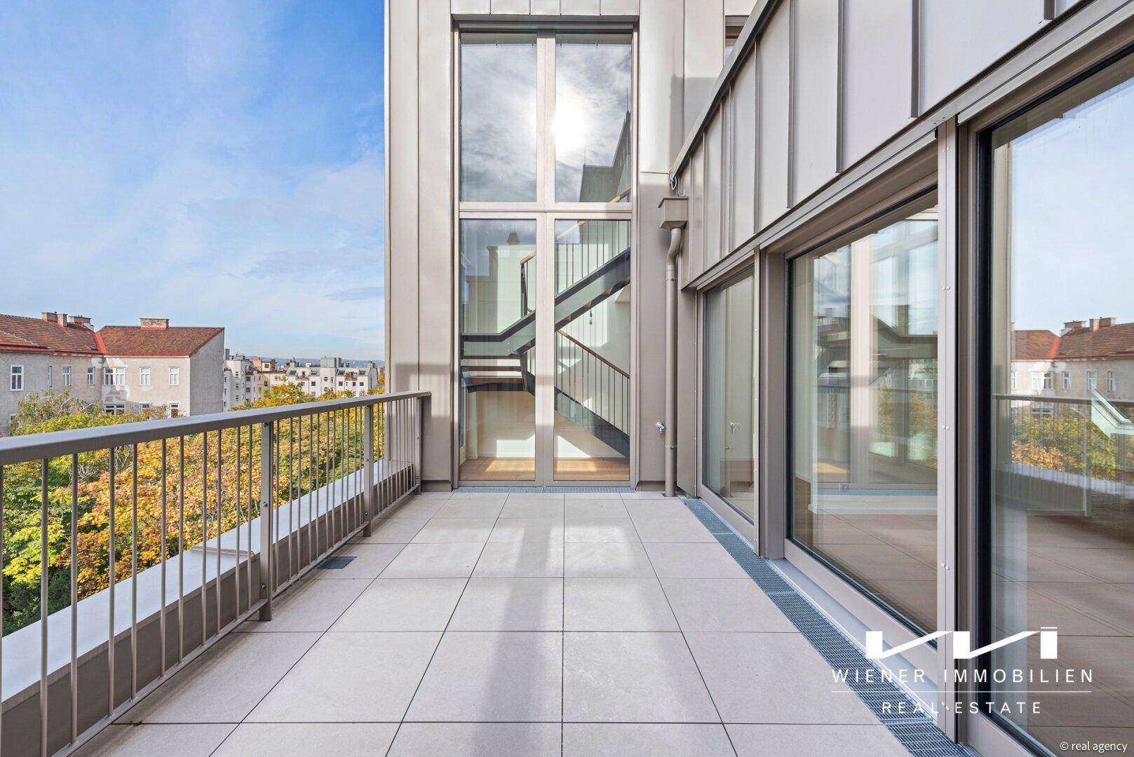Weitläufige Dachterrasse mit Fliesenboden und Panoramablick über die Stadt.