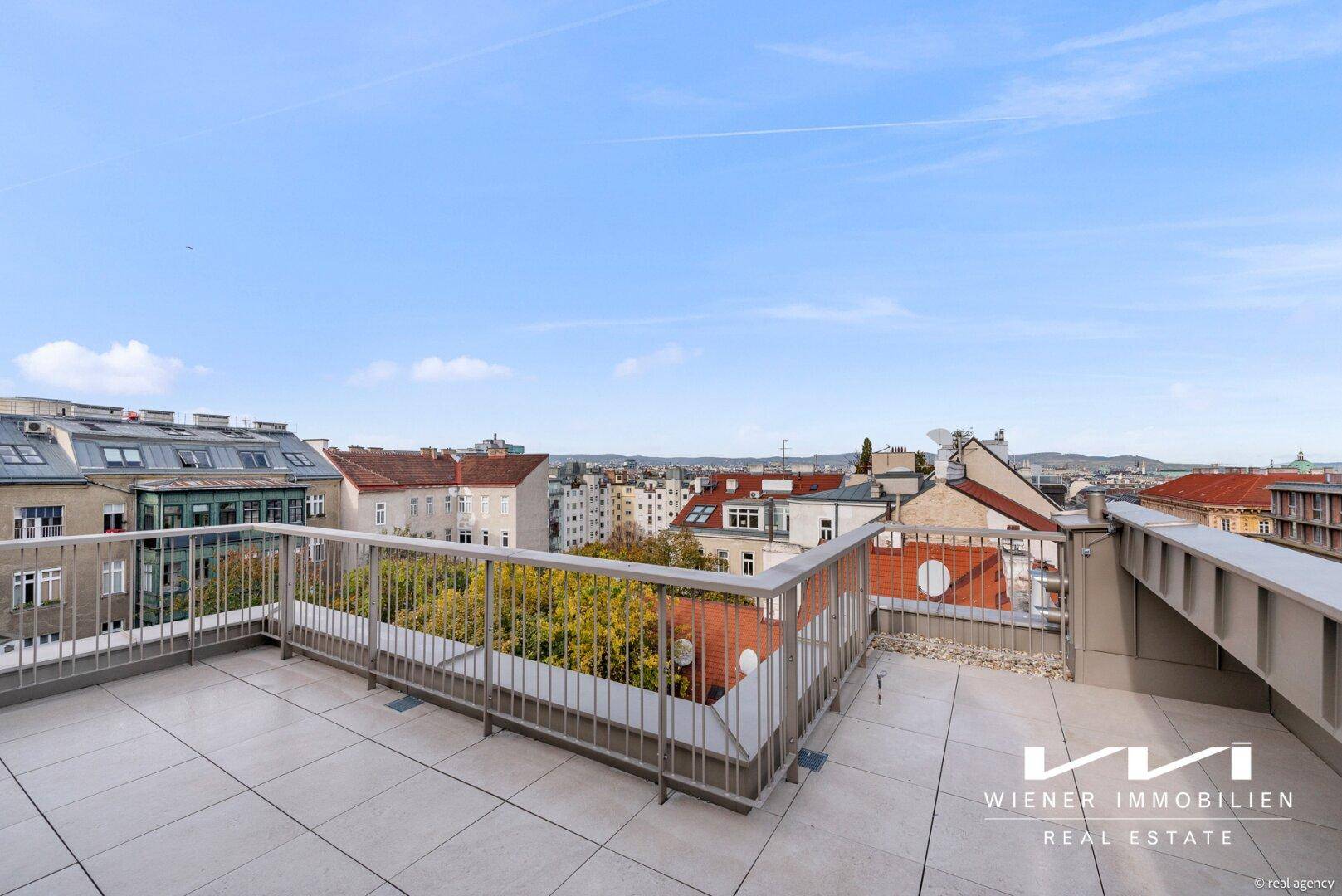 Große Dachterrasse mit Fliesenboden und weitem Blick über die Stadt und die Dächer.