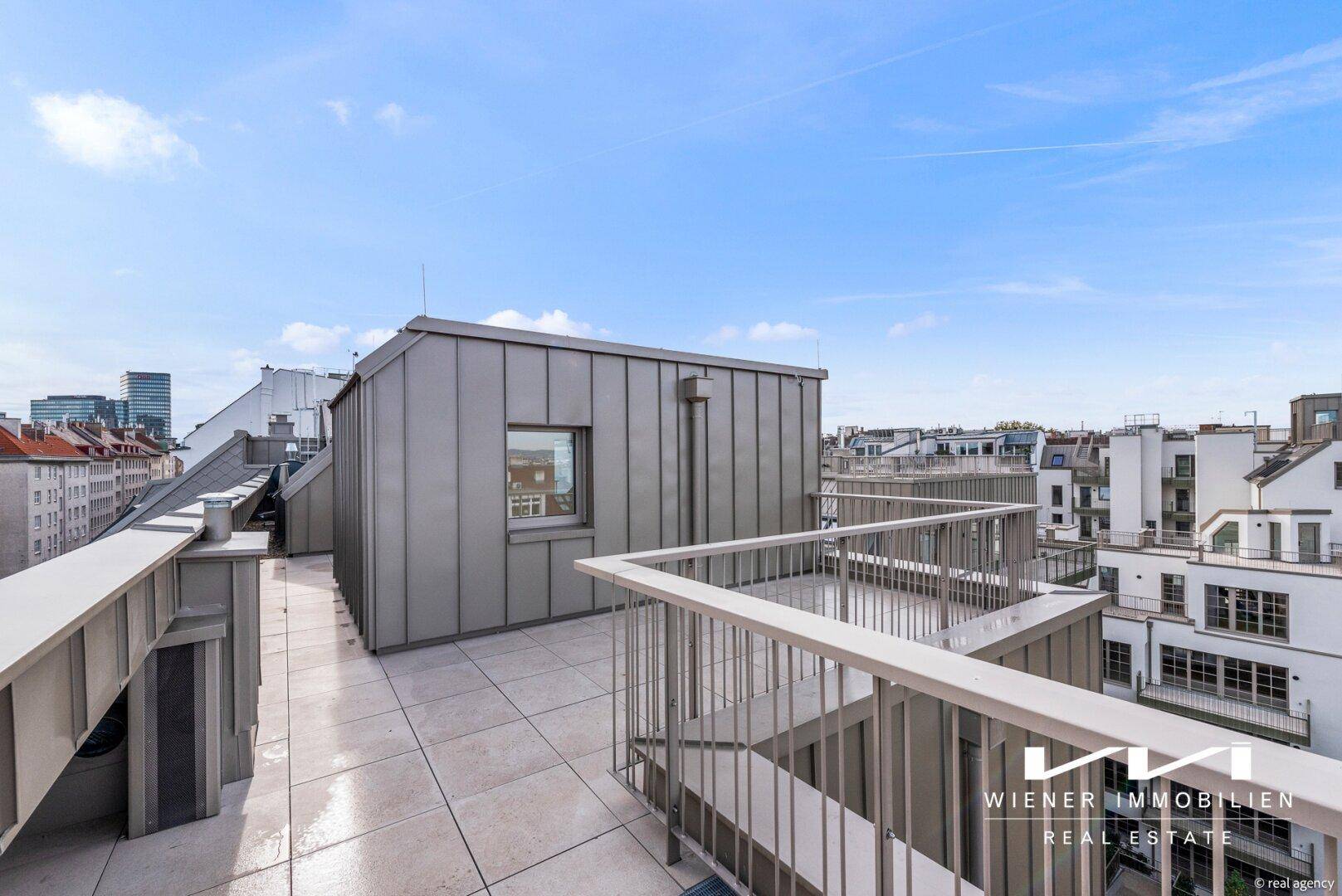 Weitläufige Dachterrasse mit moderner Architektur und Blick auf die umliegenden Gebäude.