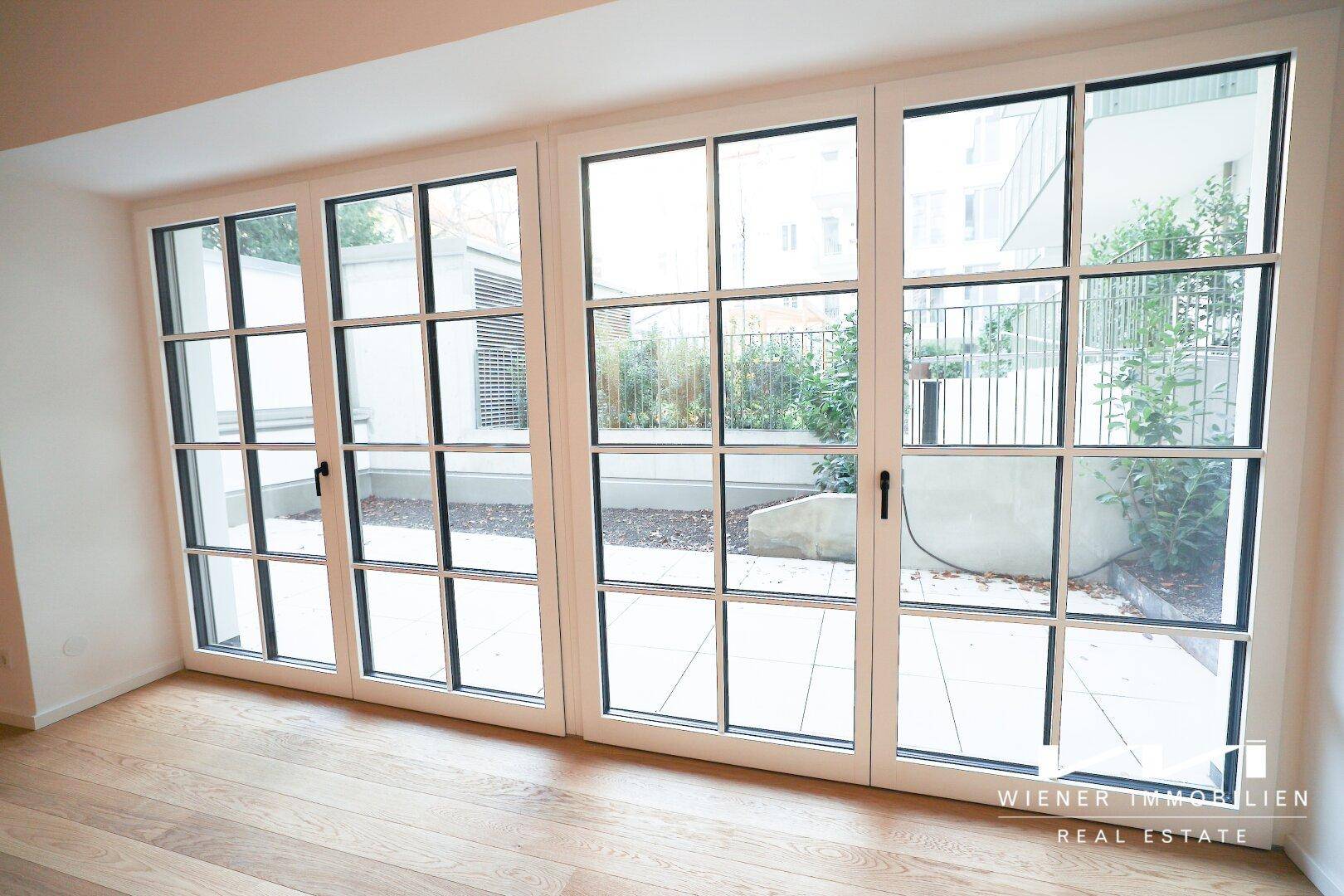 Große Fenstertüren bieten Zugang zu einem Außenbereich und lassen viel Licht in den Raum.