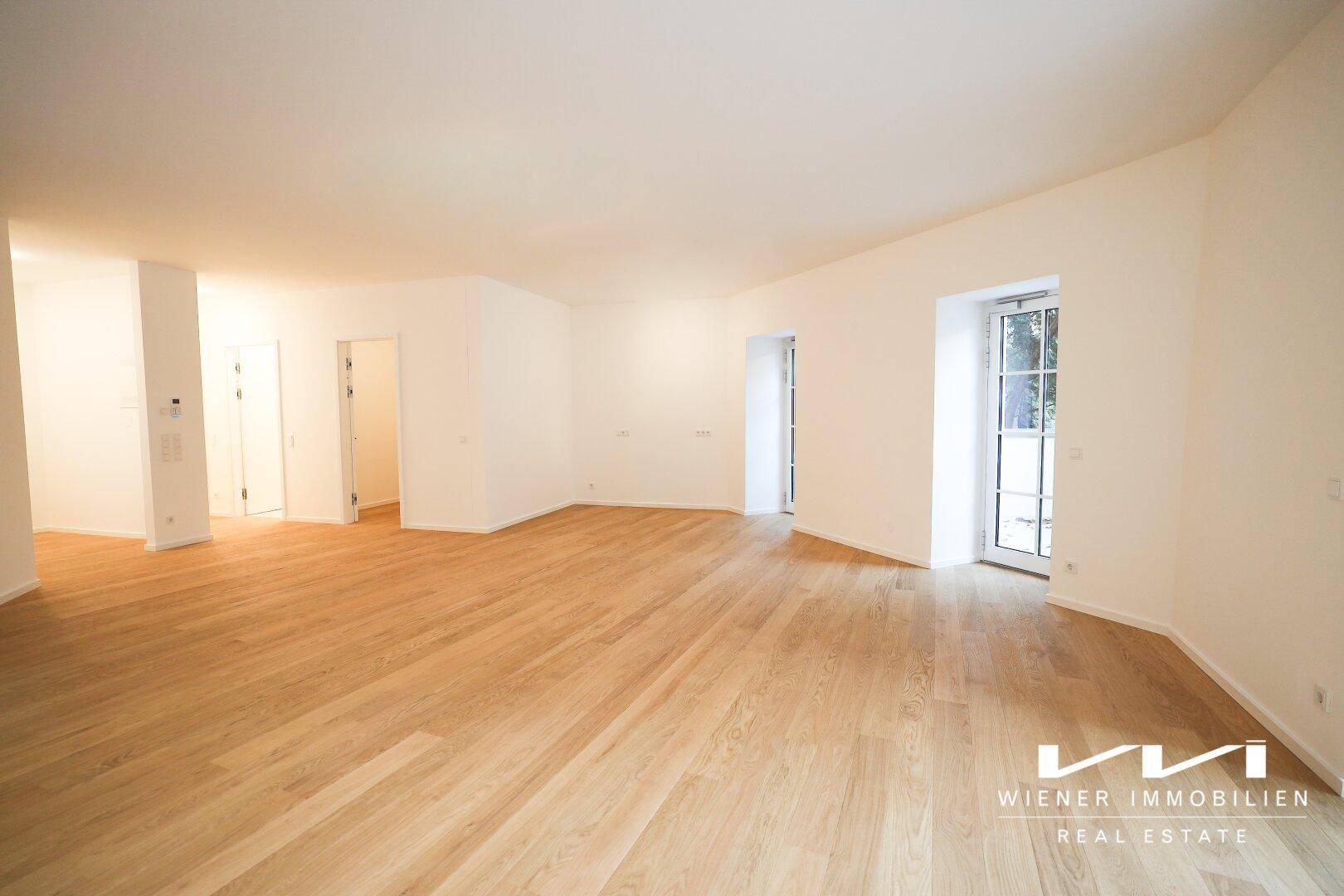 Heller Wohnbereich mit hochwertigem Parkettboden und großen Fenstern, bereit für die Einrichtung.