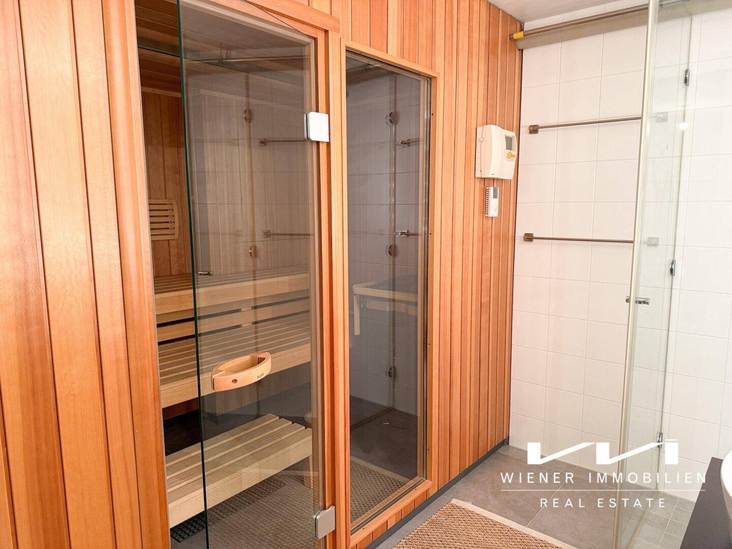 Wellnessbereich mit holzverkleideter Sauna und angrenzender Dusche.