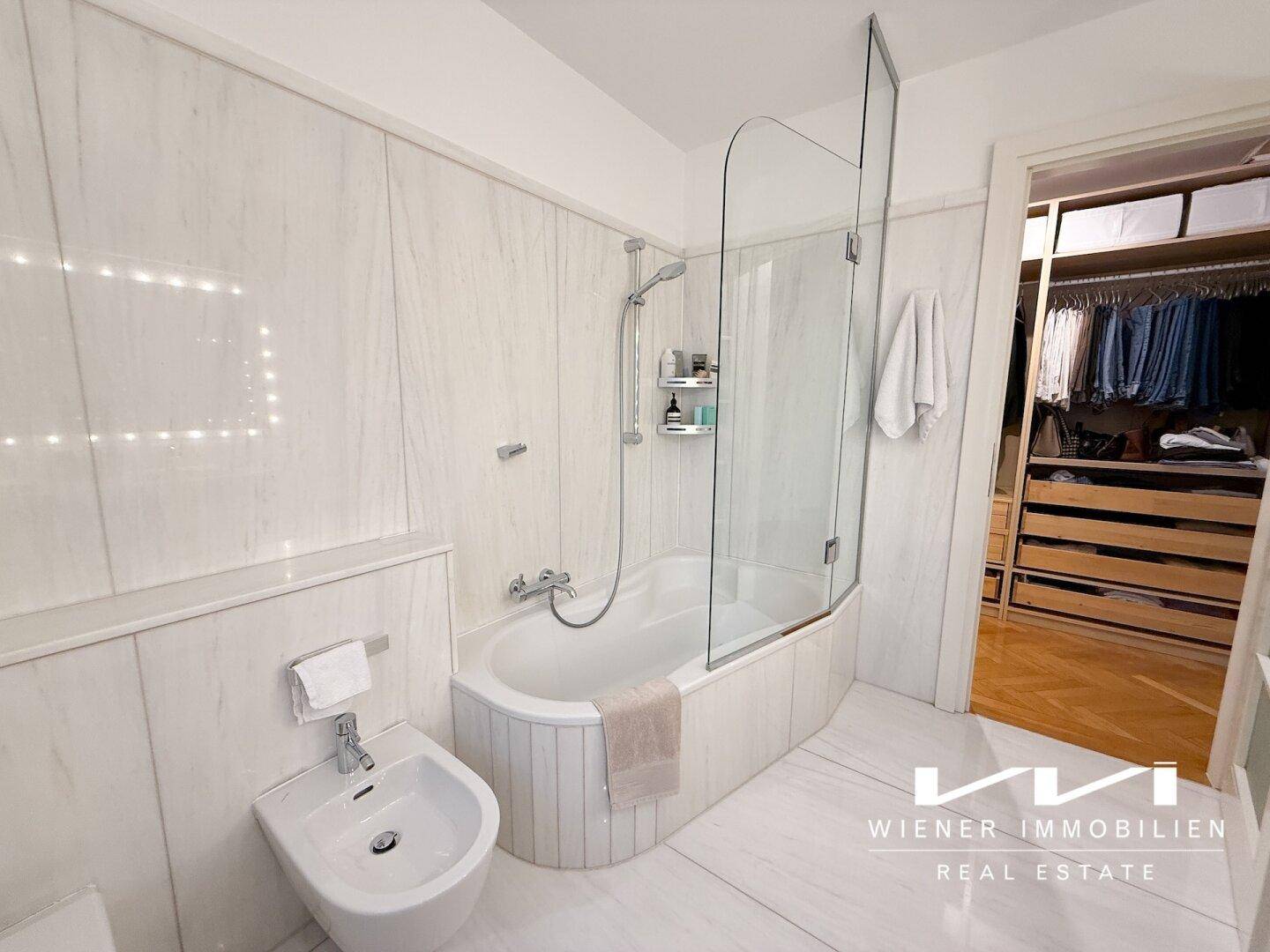 Elegantes Badezimmer mit Badewanne, Bidet und Zugang zu einem begehbaren Kleiderschrank.