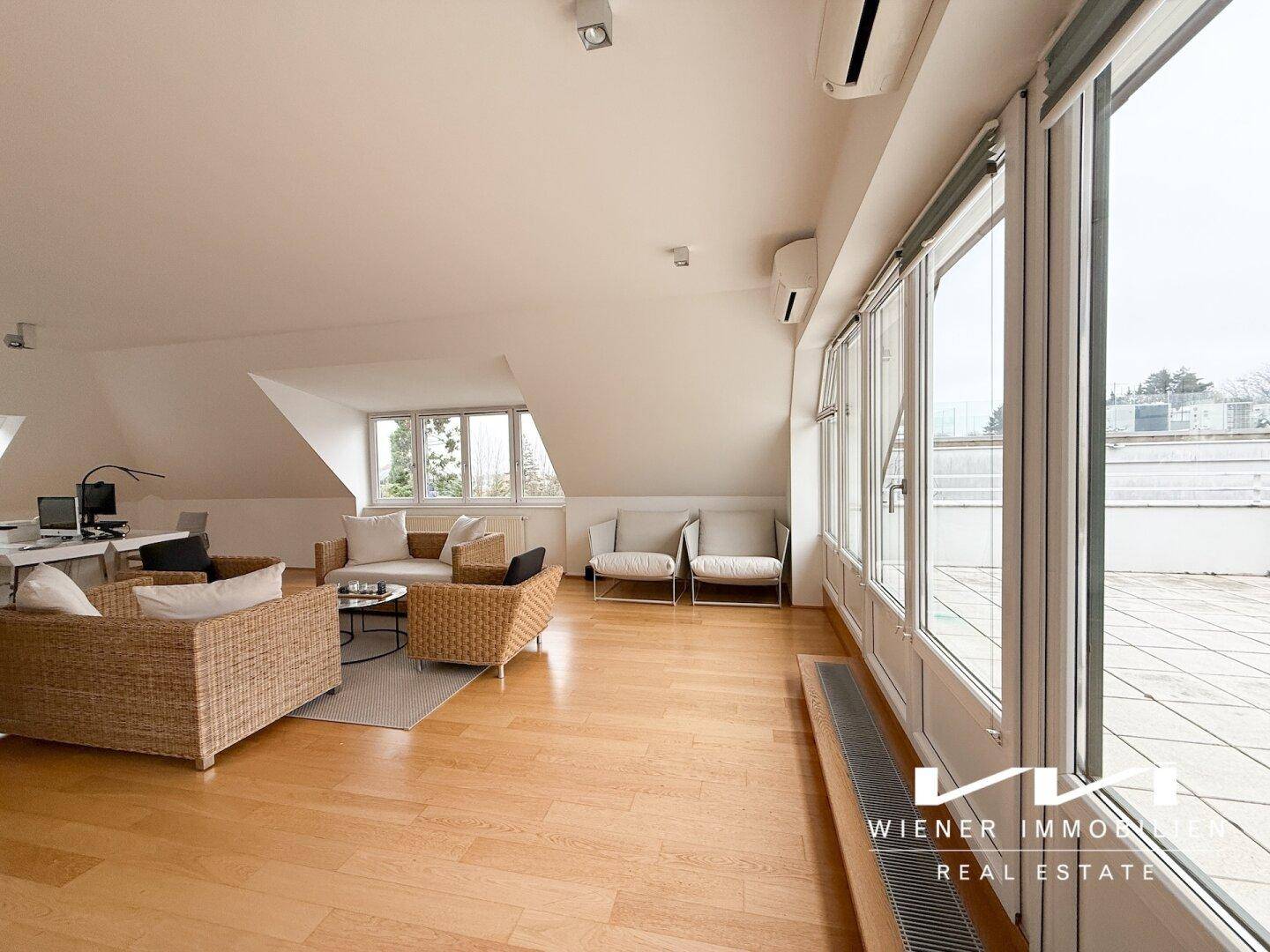 Weitläufiges Wohnzimmer im Dachgeschoss mit großen Fenstern, Klimaanlage und Zugang zur Dachterrasse.
