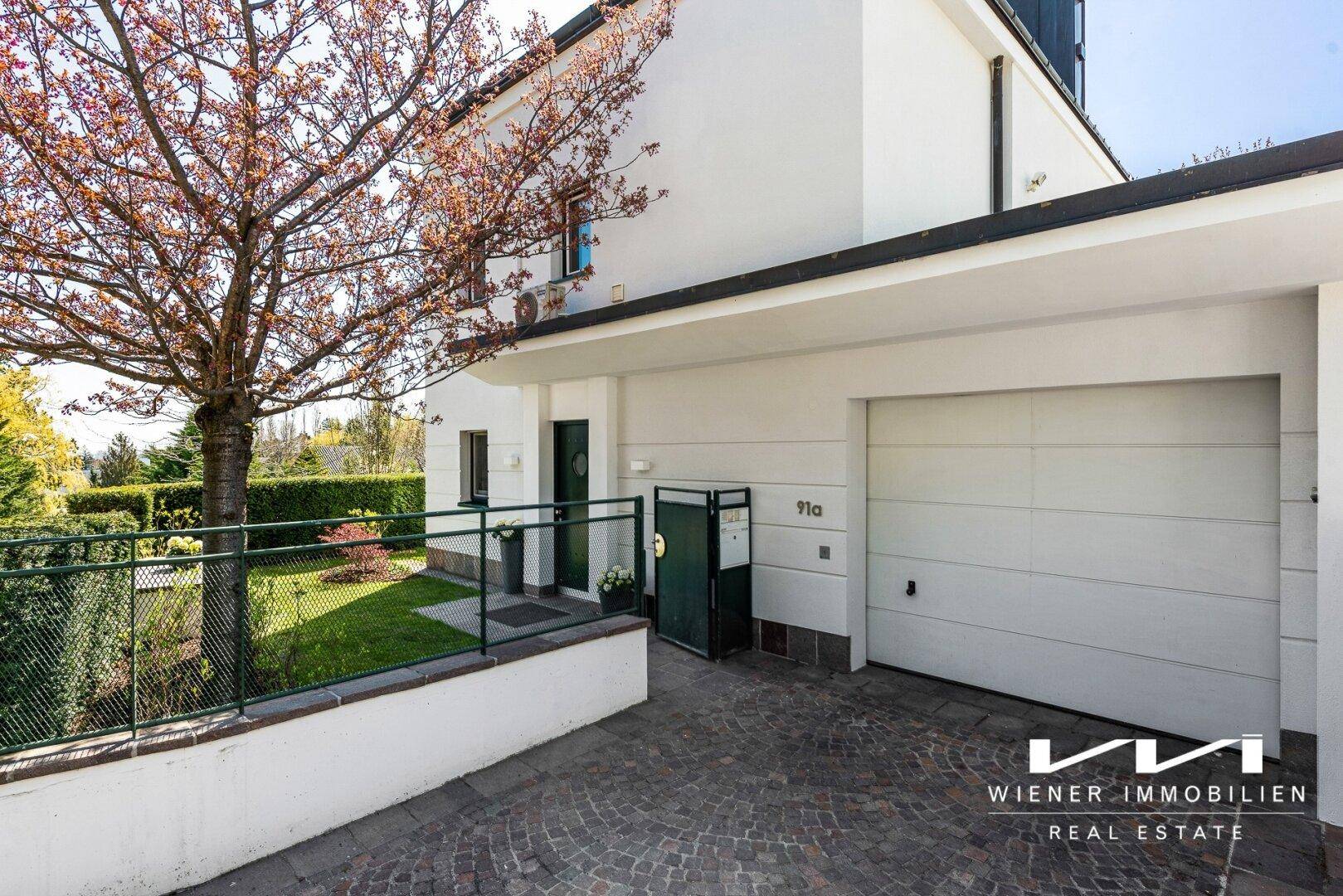 Modernes Einfamilienhaus mit integrierter Garage und gepflasterter Auffahrt.