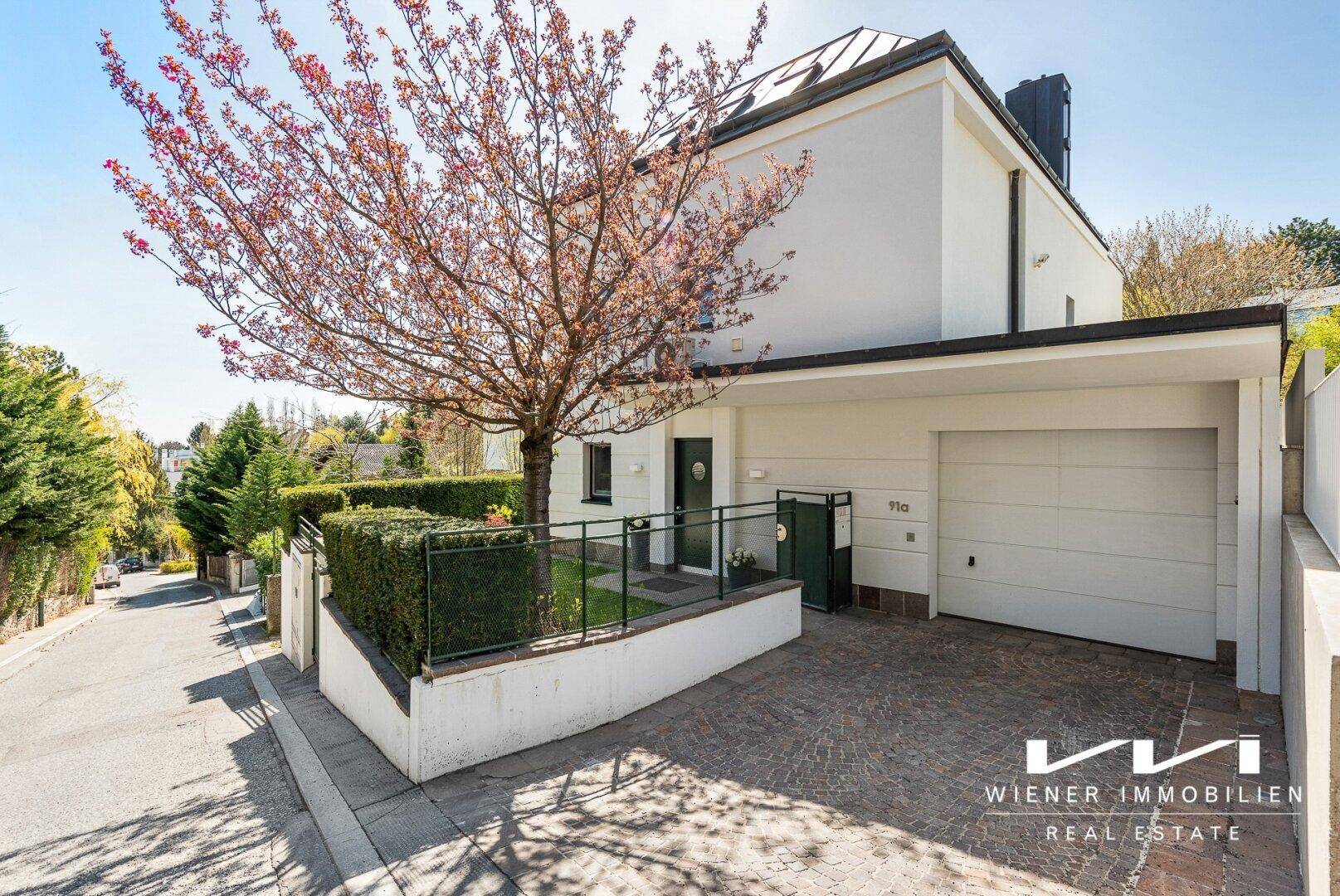 Modernes Einfamilienhaus mit Garage, gepflasterter Auffahrt und Zugang zur Straße.