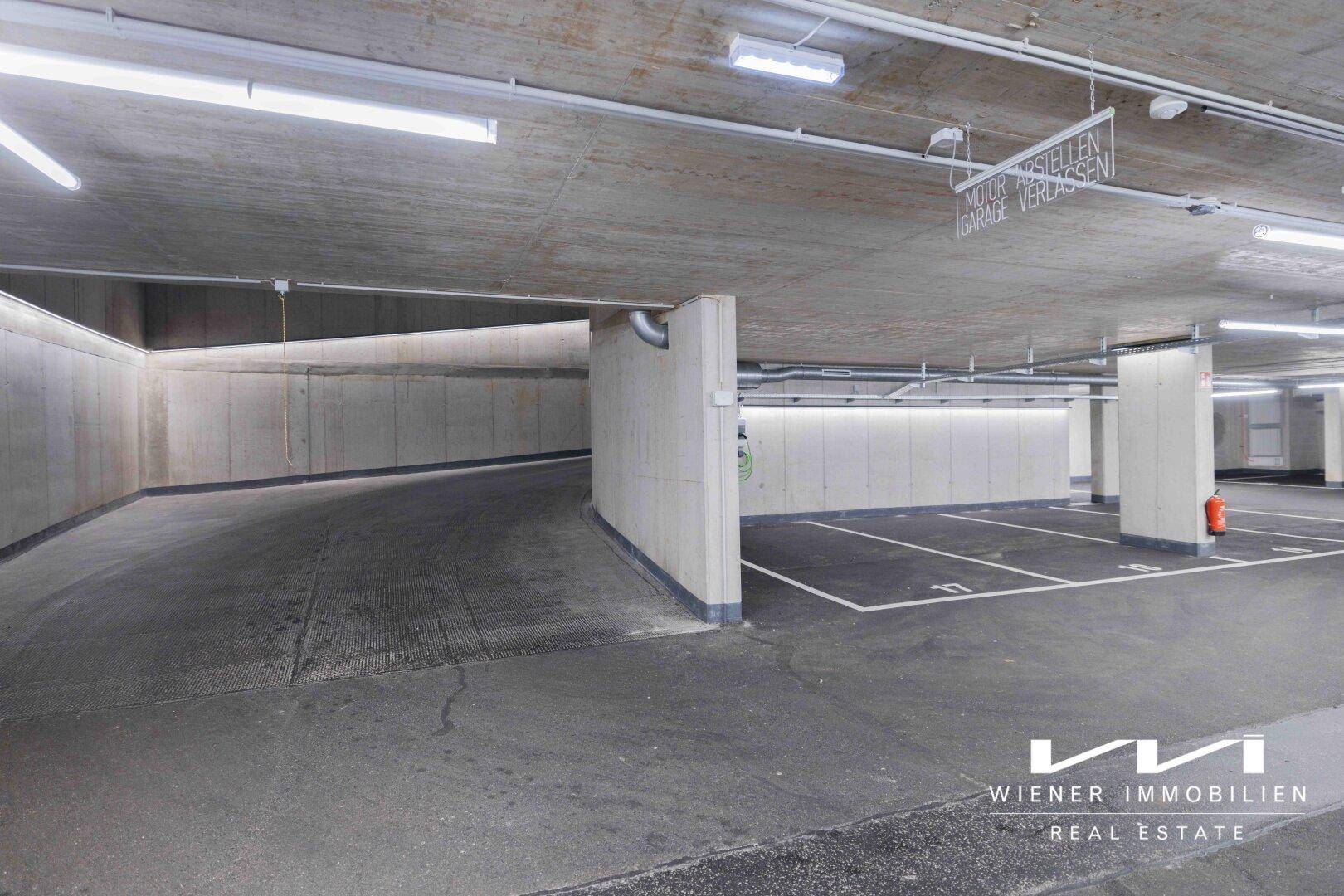 Kurvige Rampe in einer Tiefgarage, die zu weiteren Stellplätzen führt, mit minimalistischer Beleuchtung.