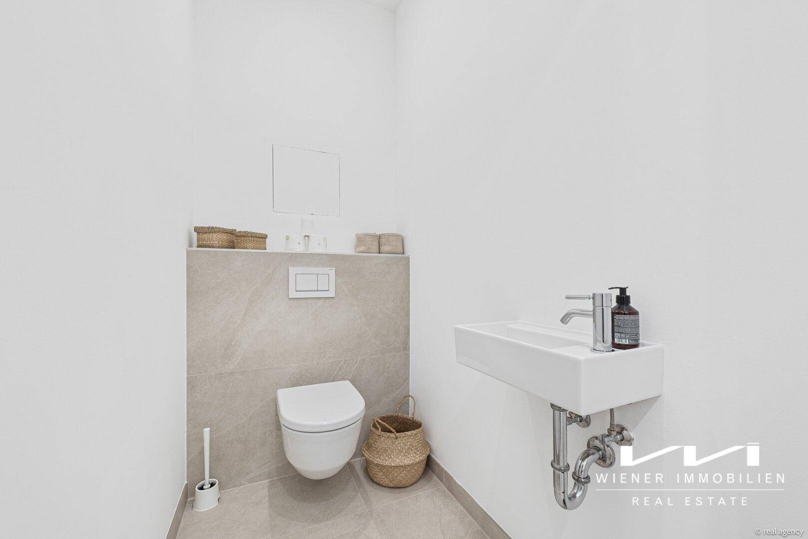 Modernes Gäste-WC mit wandhängender Toilette und minimalistischem Waschbecken.