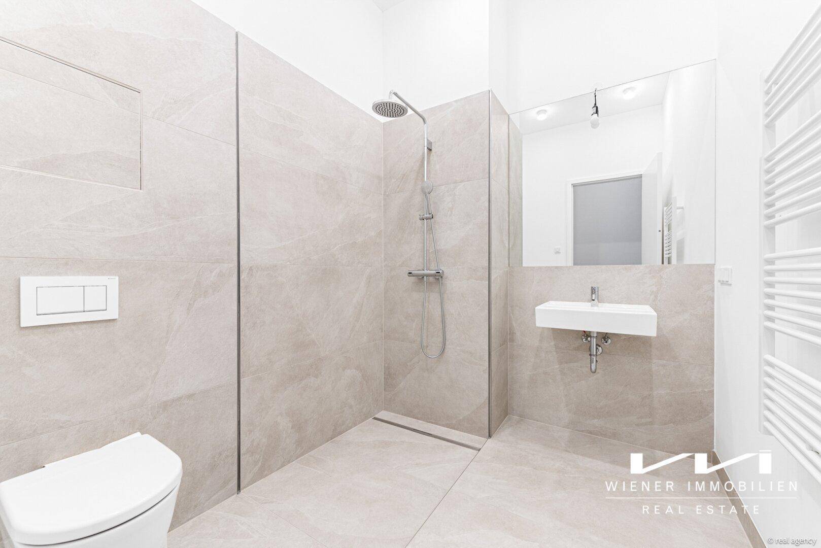 Modernes Badezimmer mit bodengleicher Dusche, Wand-WC und großem Spiegel.