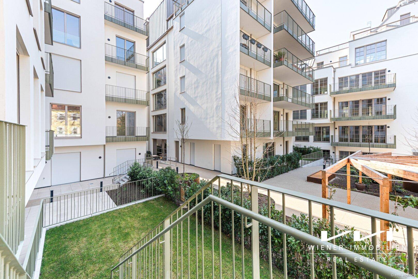 Moderne Wohnanlage mit mehreren Balkonen, begrüntem Innenhof und Zugang zu den verschiedenen Gebäudeteilen.
