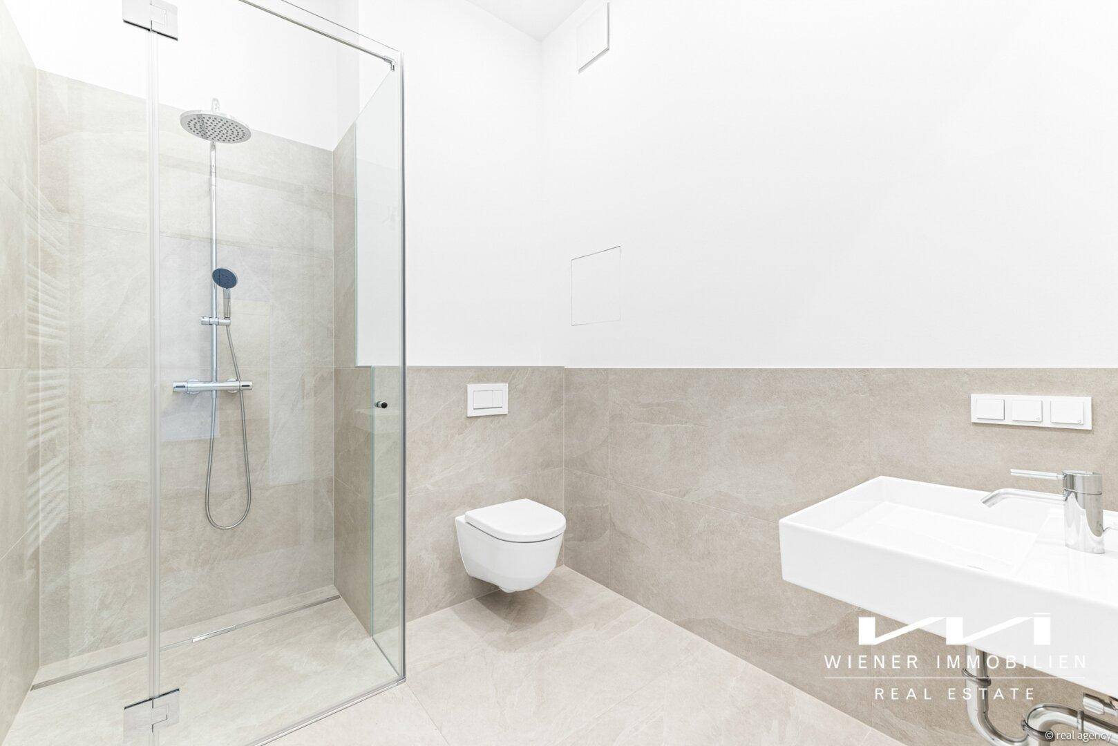 Modernes Badezimmer mit ebenerdiger Regendusche, wandhängendem WC und eleganten grauen Fliesen.
