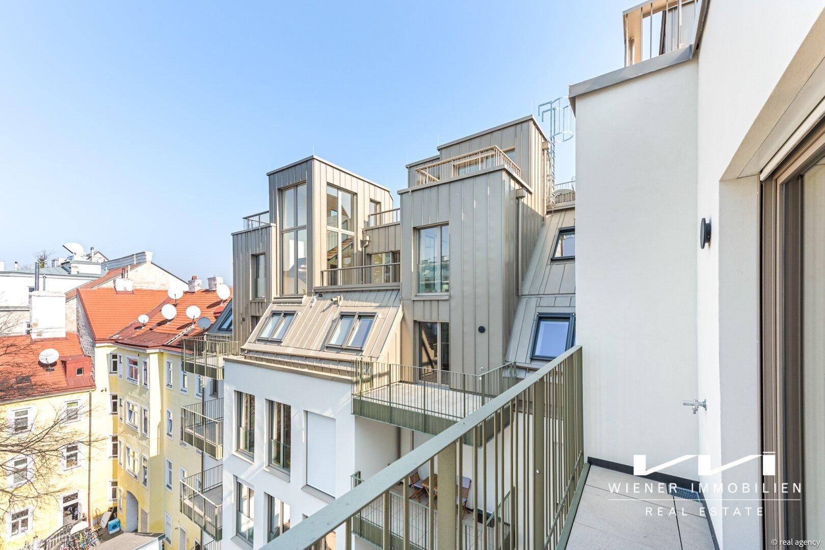 Balkon mit Metallgeländer und weitem Blick über die Dächer der Stadt.