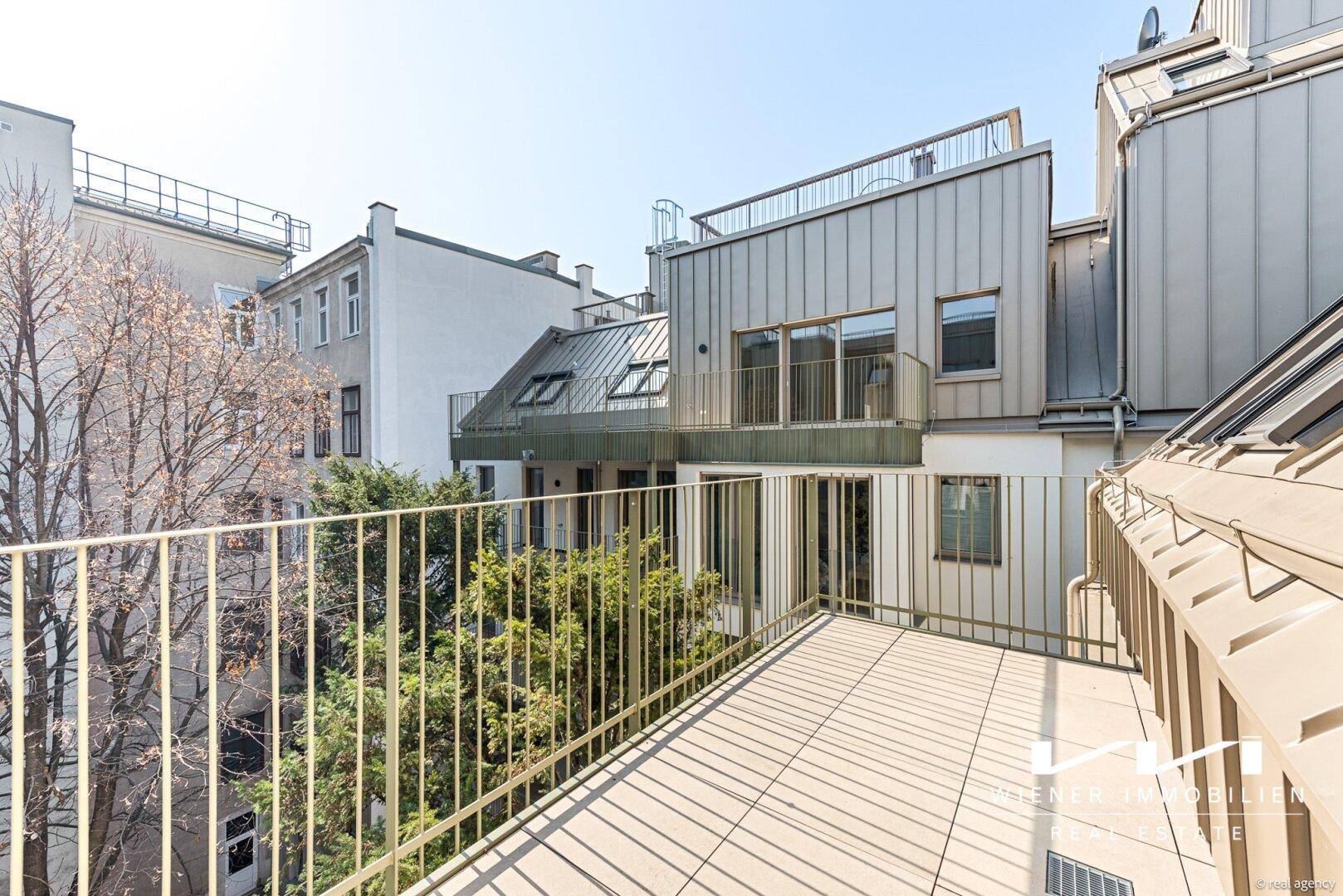 Große Dachterrasse mit Fliesenboden und Blick auf die umliegenden Gebäude.