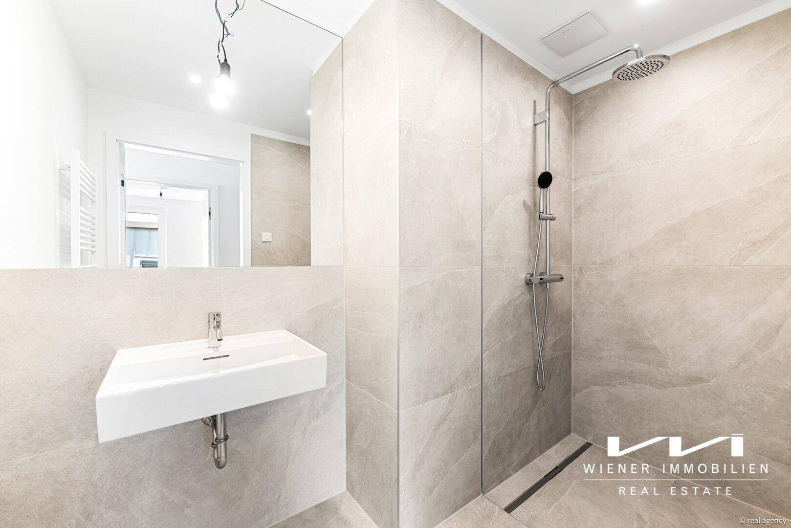 Modernes Badezimmer mit ebenerdiger Dusche, Einzelwaschbecken und großem Spiegel über dem Waschtisch.