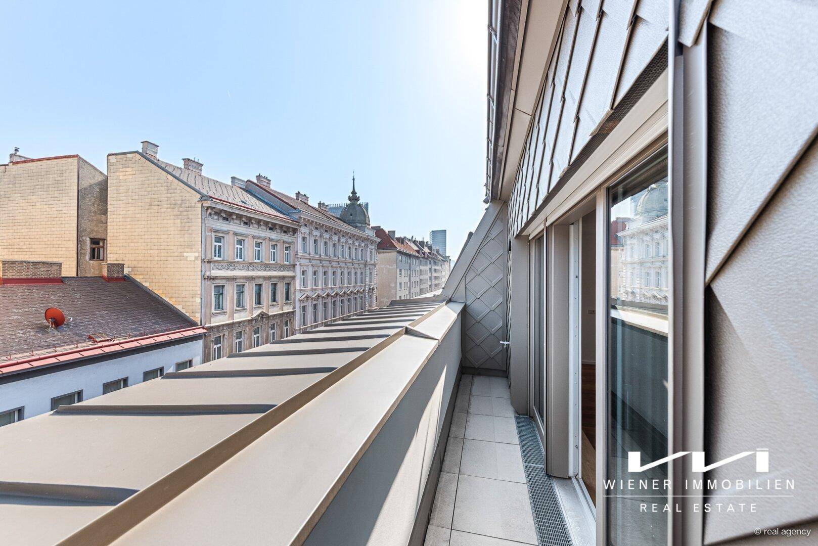 Langer Balkon mit Stadtblick und moderner Metallverkleidung an der Fassade.