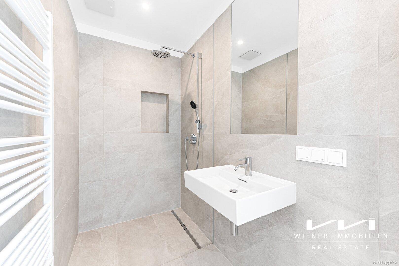 Modernes Badezimmer mit begehbarer Dusche, Regendusche und beheiztem Handtuchhalter.