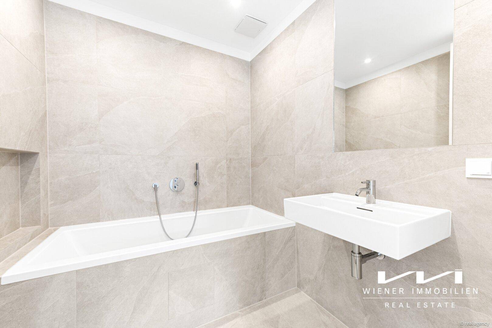 Elegantes Badezimmer mit Badewanne, modernem Waschbecken und hellen Fliesen.