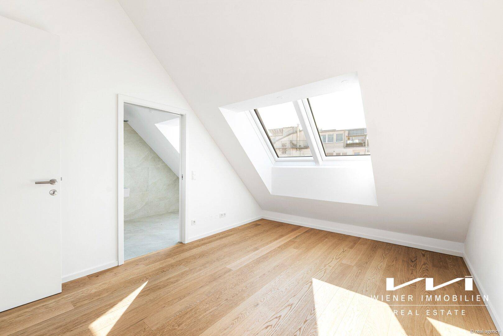 Helles Zimmer im Dachgeschoss mit Holzboden und einem großen Dachfenster, ideal als Schlaf- oder Arbeitszimmer.