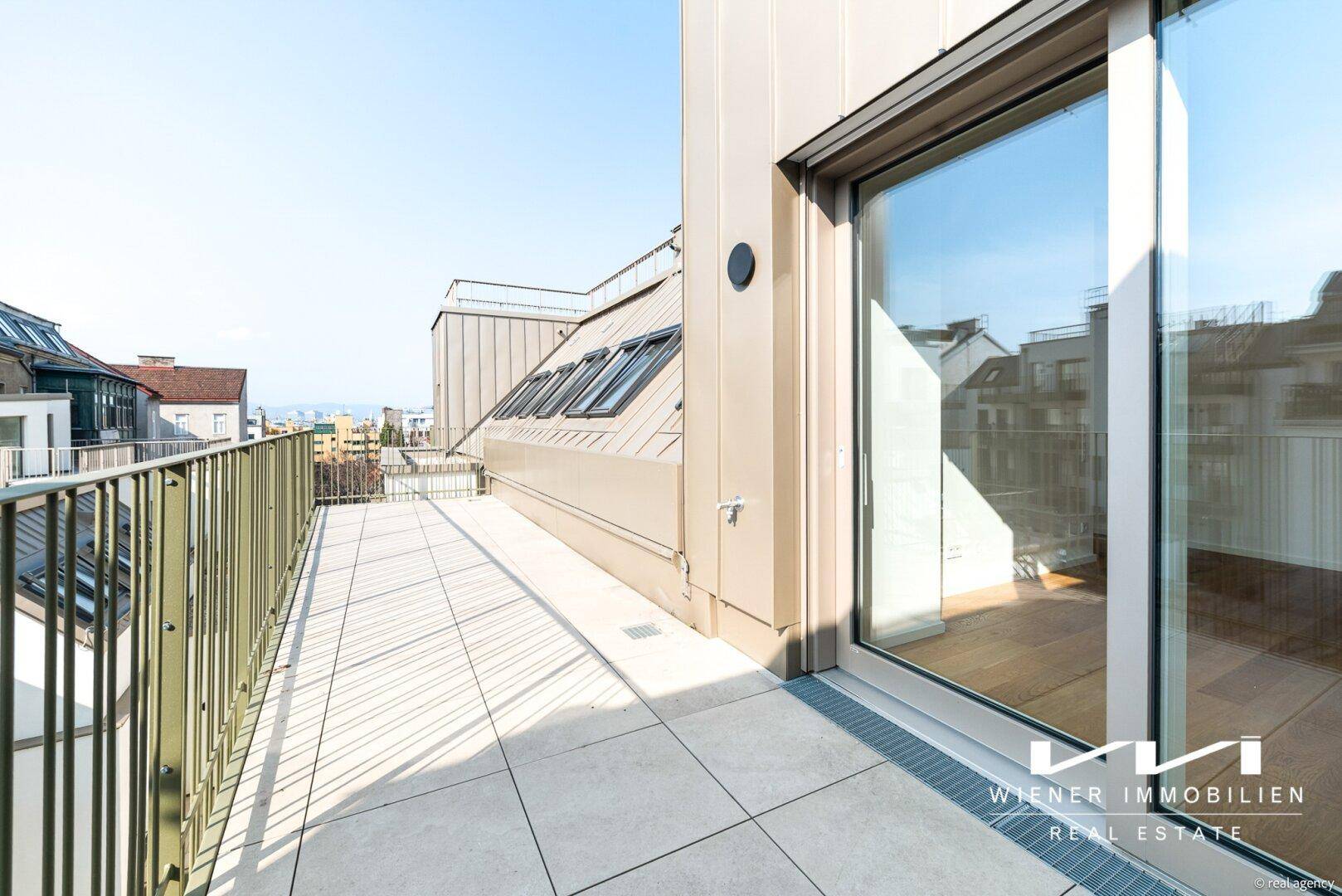 Sonnenverwöhnter Balkon mit Fliesenboden und Metallgeländer, der einen weiten Blick über die Stadt ermöglicht.