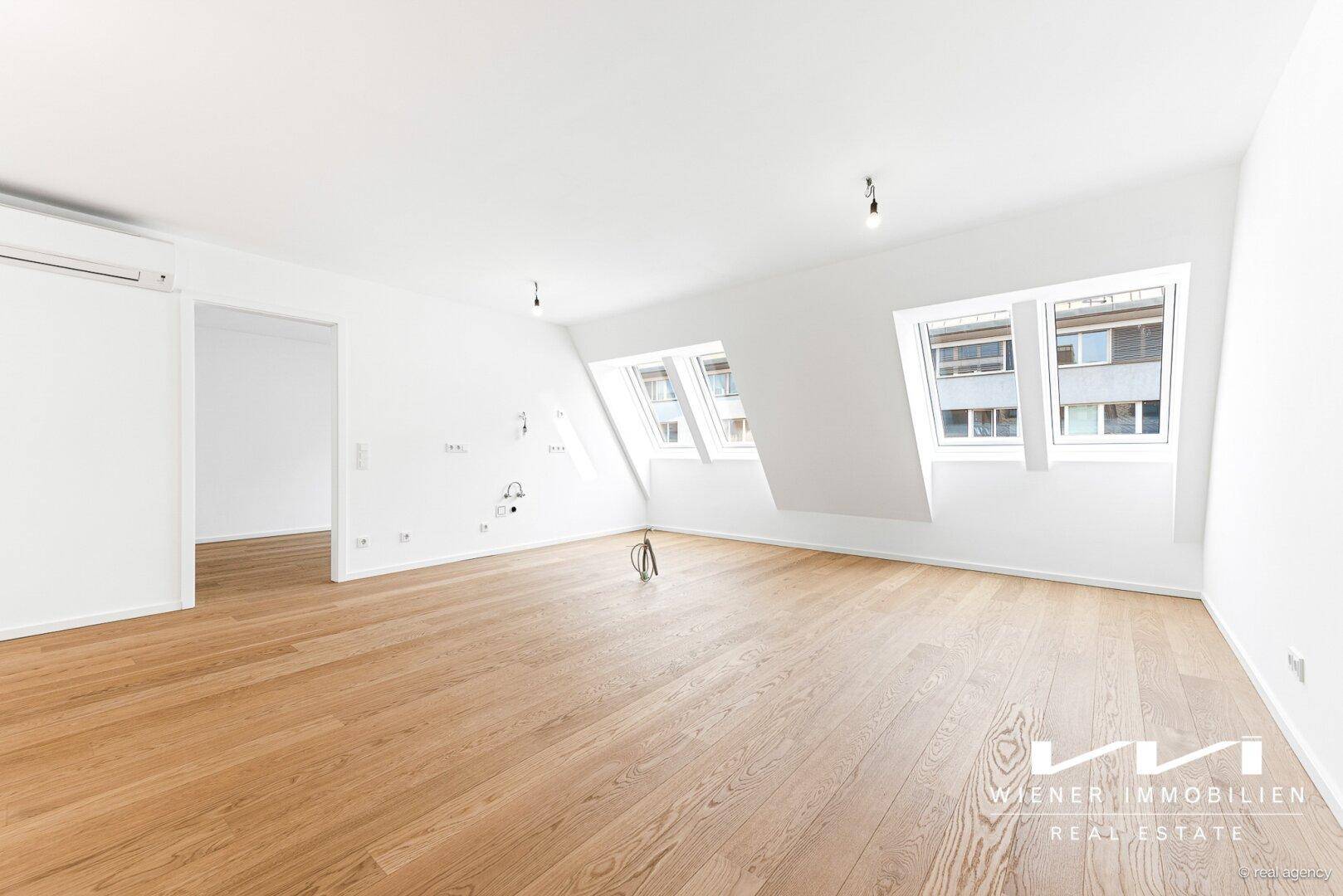 Geräumiger, heller Wohnbereich mit Holzboden, Dachschrägenfenstern und moderner Ausstattung.