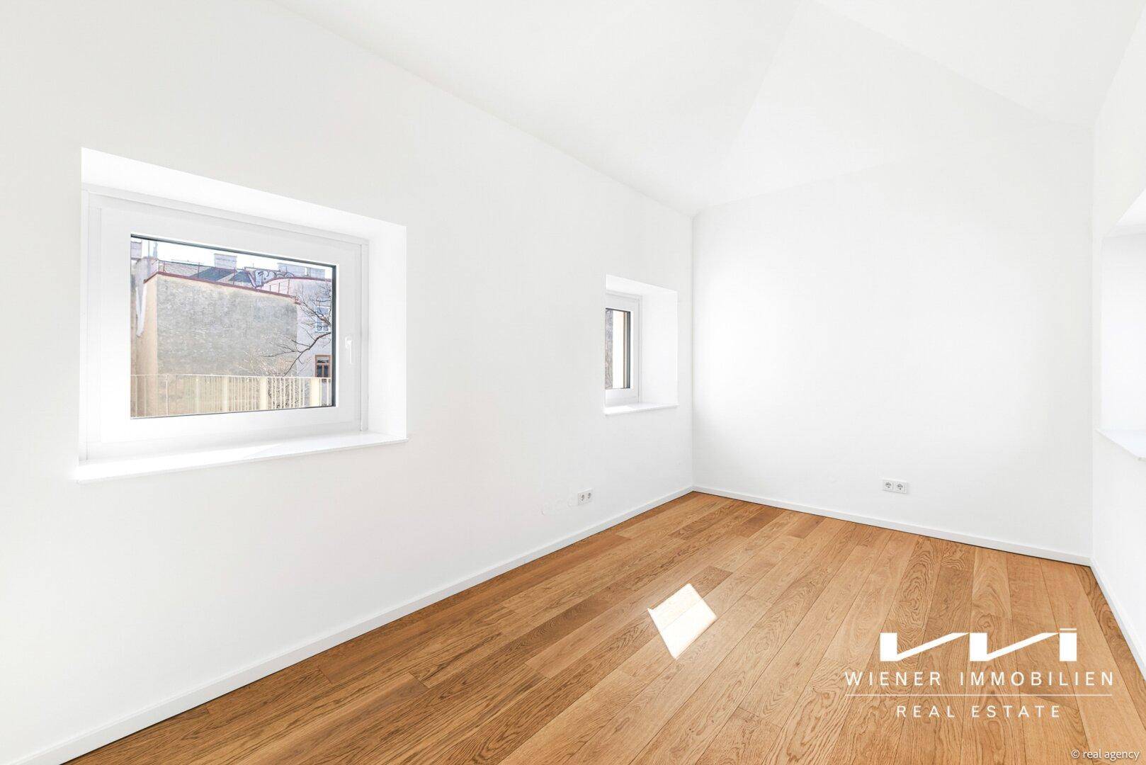 Helles Schlafzimmer im Dachgeschoss mit Holzboden und schrägen Wänden.