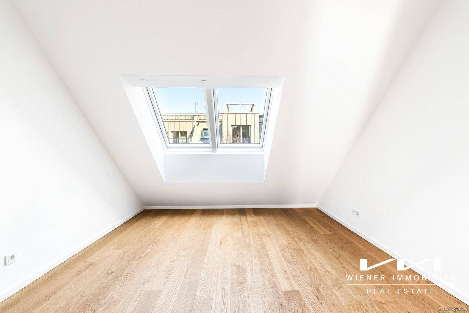 Helles Zimmer im Dachgeschoss mit Holzboden und großem Dachfenster für viel Tageslicht.
