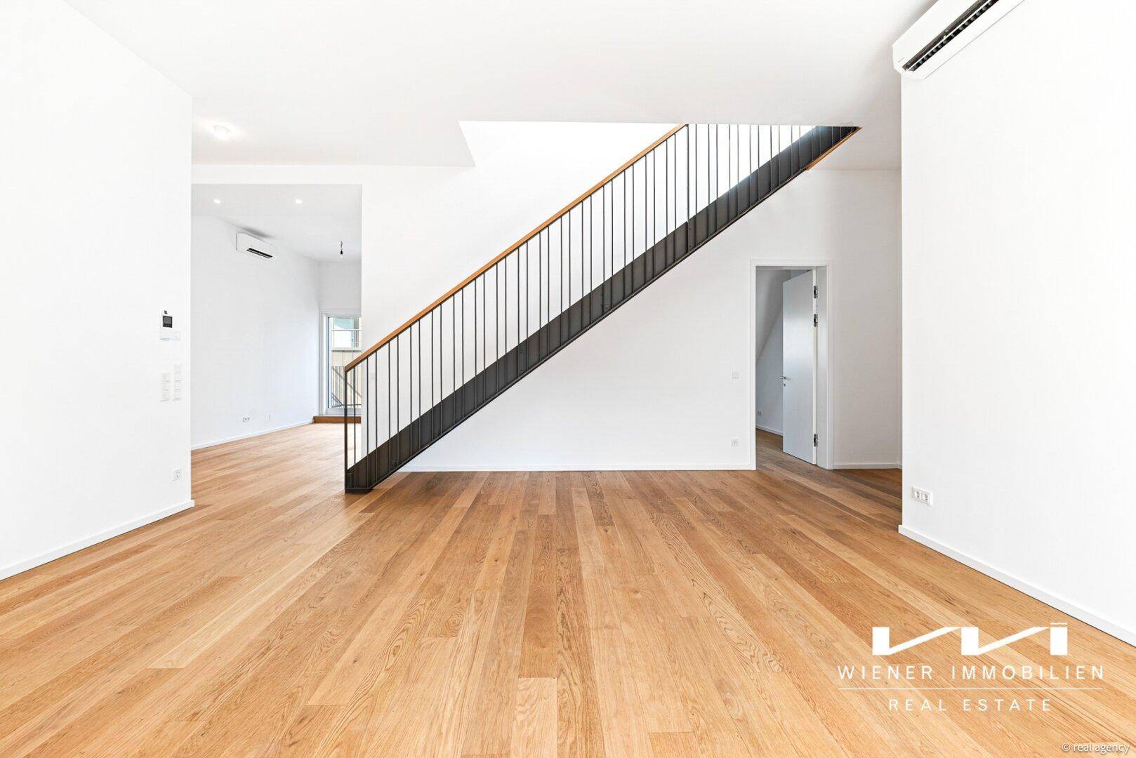 Geräumiger Wohnbereich mit Eichenparkett und moderner Treppe als zentrales Element.