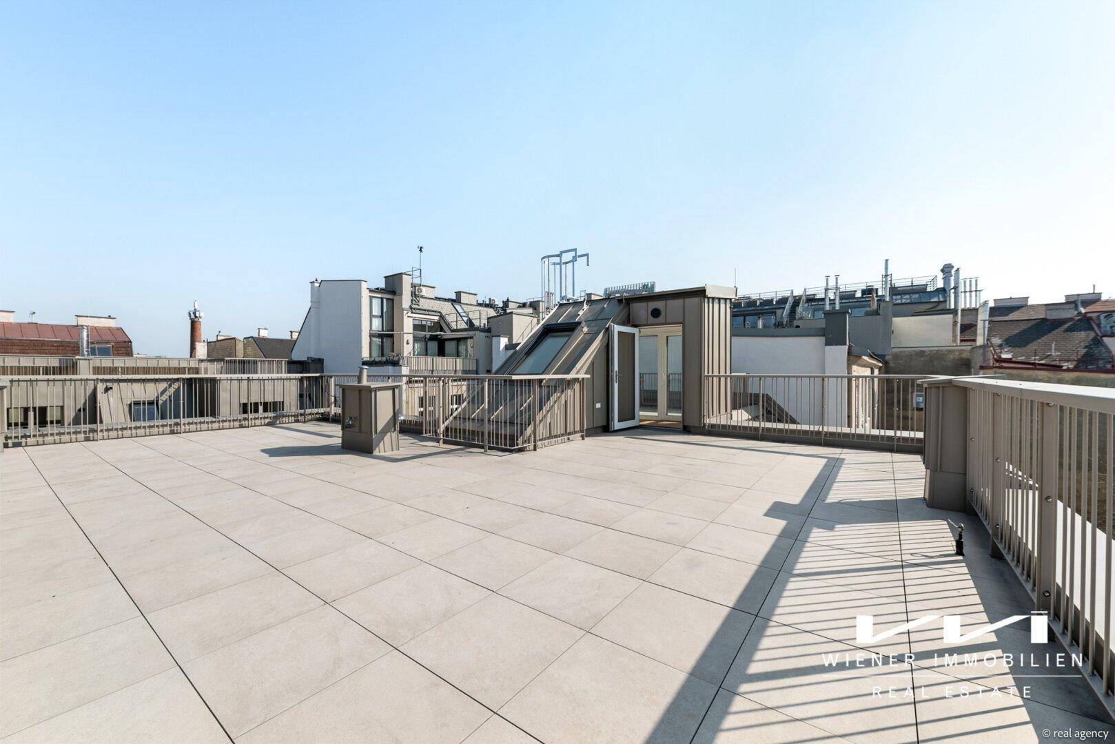 Geräumige Dachterrasse mit Fliesenboden und weitem Blick über die Stadt.