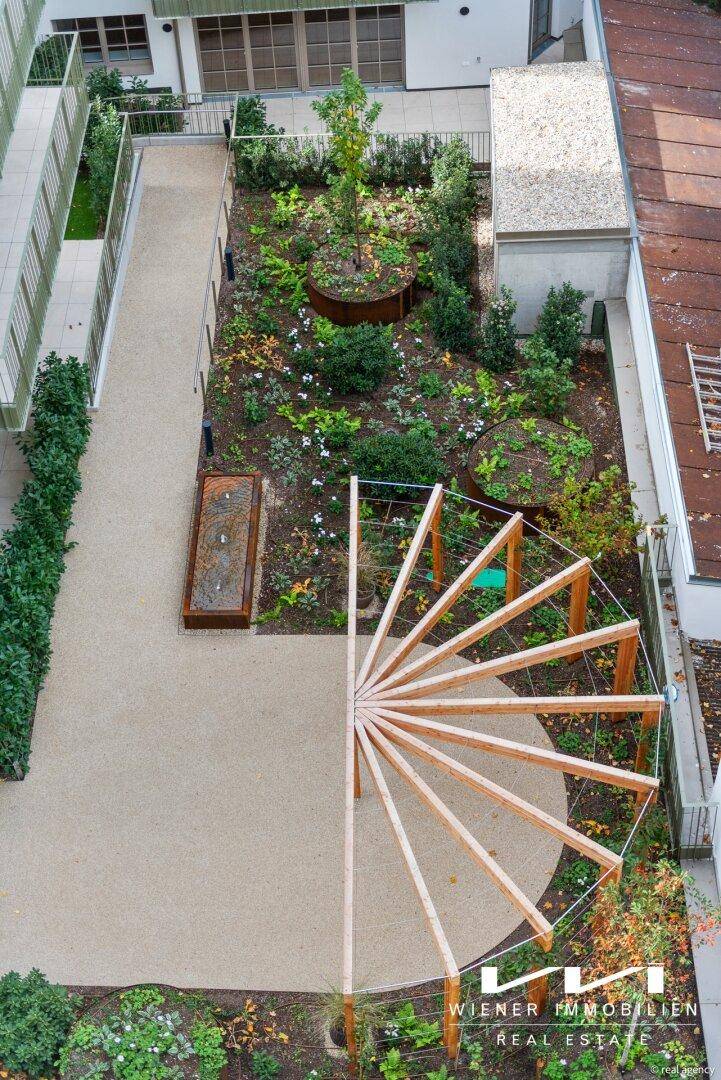 Grüner Innenhofgarten von oben gesehen mit einer modernen Holzkonstruktion und Bepflanzung.