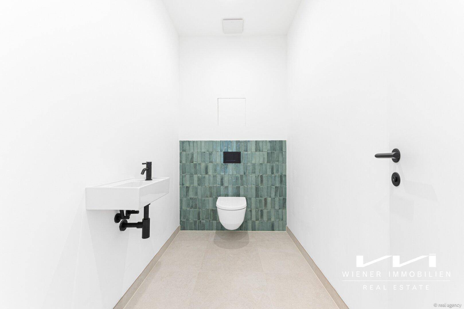Modernes Gäste-WC mit Wand-WC und grünem Fliesenakzent.