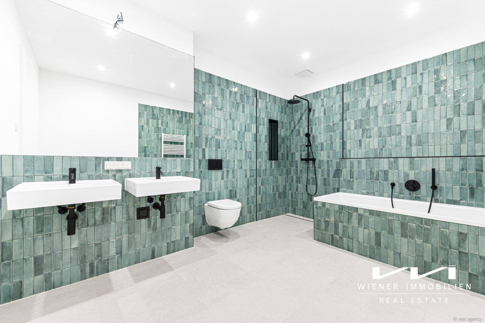 Modernes Badezimmer mit grünen Fliesen, Doppelwaschbecken, Badewanne und Dusche.