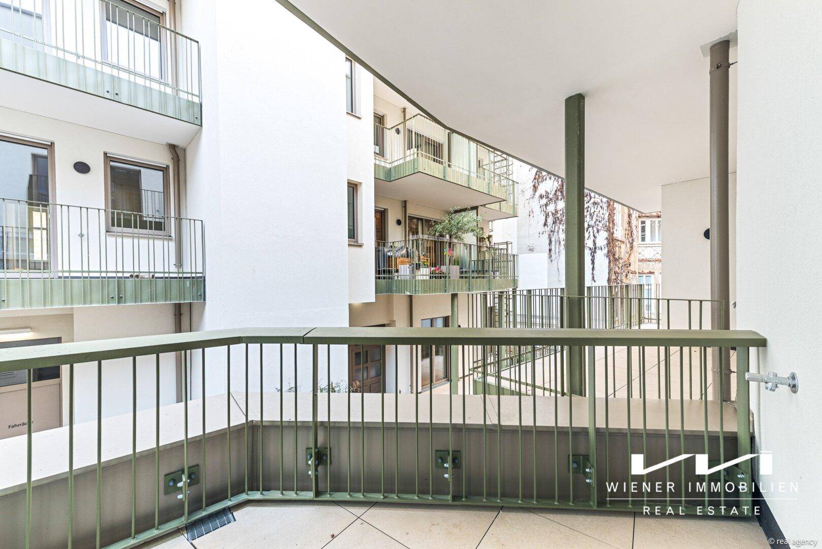 Balkon mit Metallgeländer und Blick auf den Innenhof des Gebäudes.