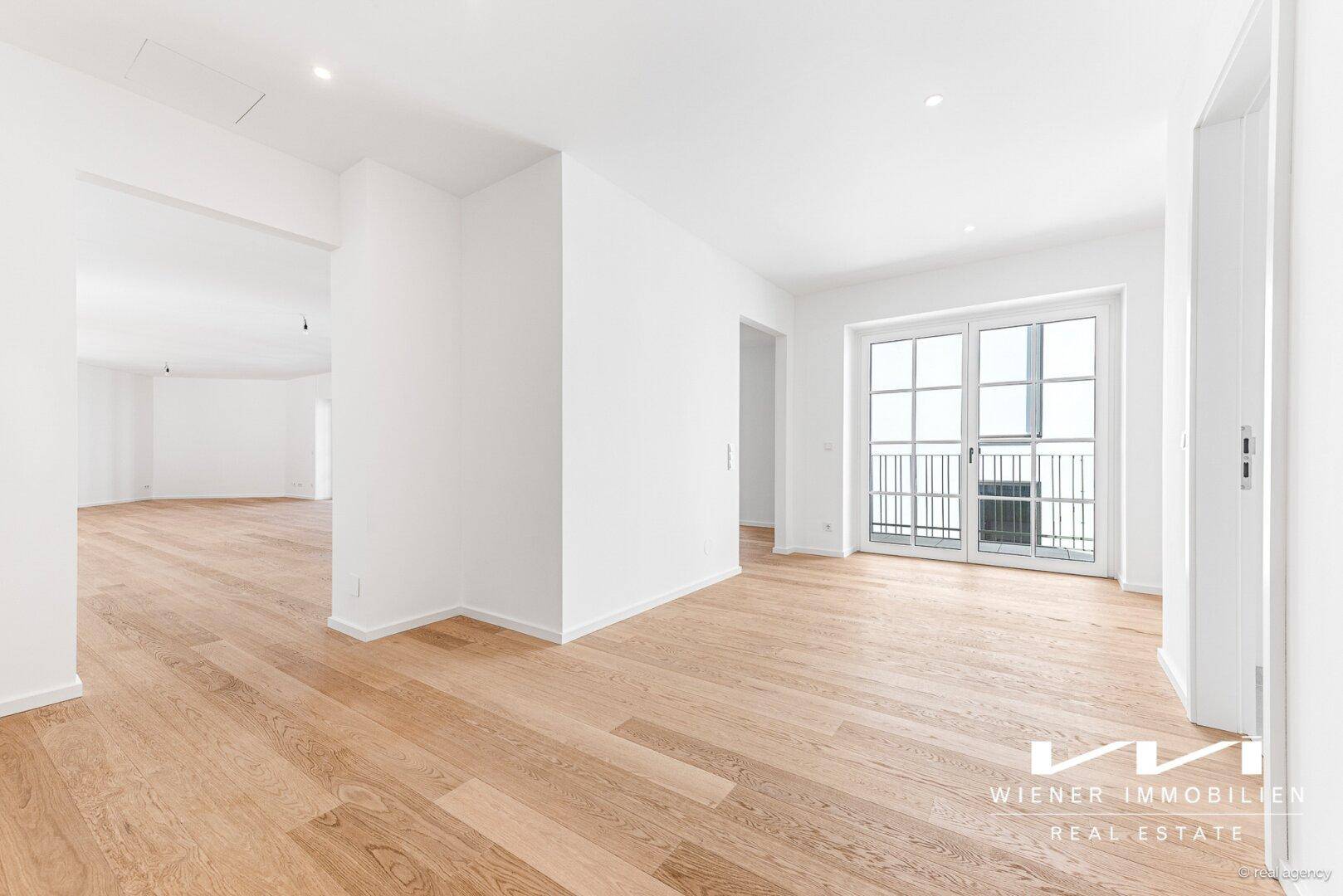 Heller Raum mit Holzparkettboden und Zugang zu einem französischen Balkon.