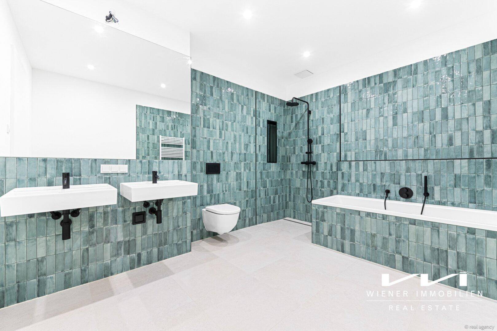 Modernes Badezimmer mit doppelten Waschbecken, Badewanne und auffälligen grünen Fliesen.