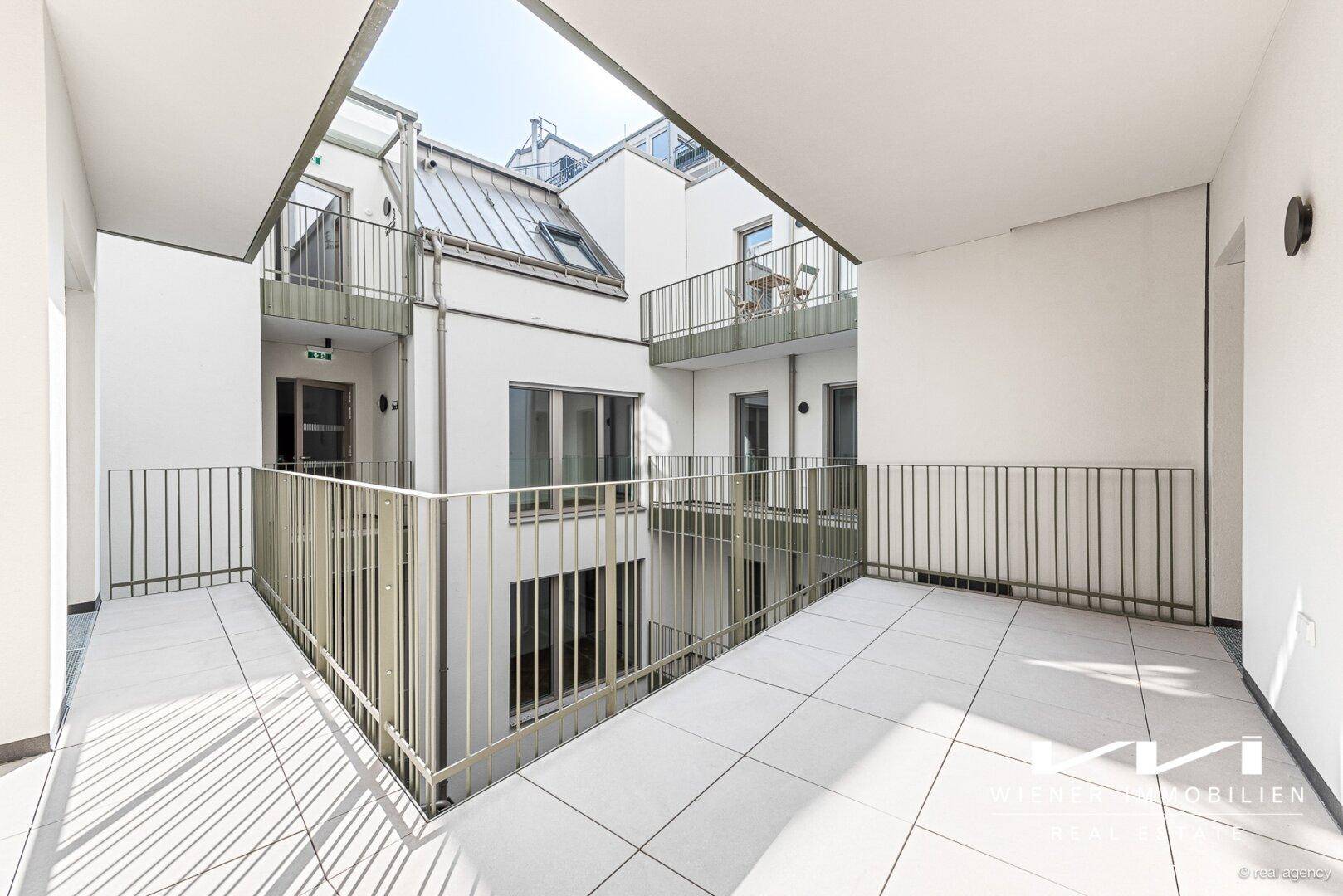 Moderner Gebäudekomplex mit offenen Gängen und Blick auf den Innenhof.