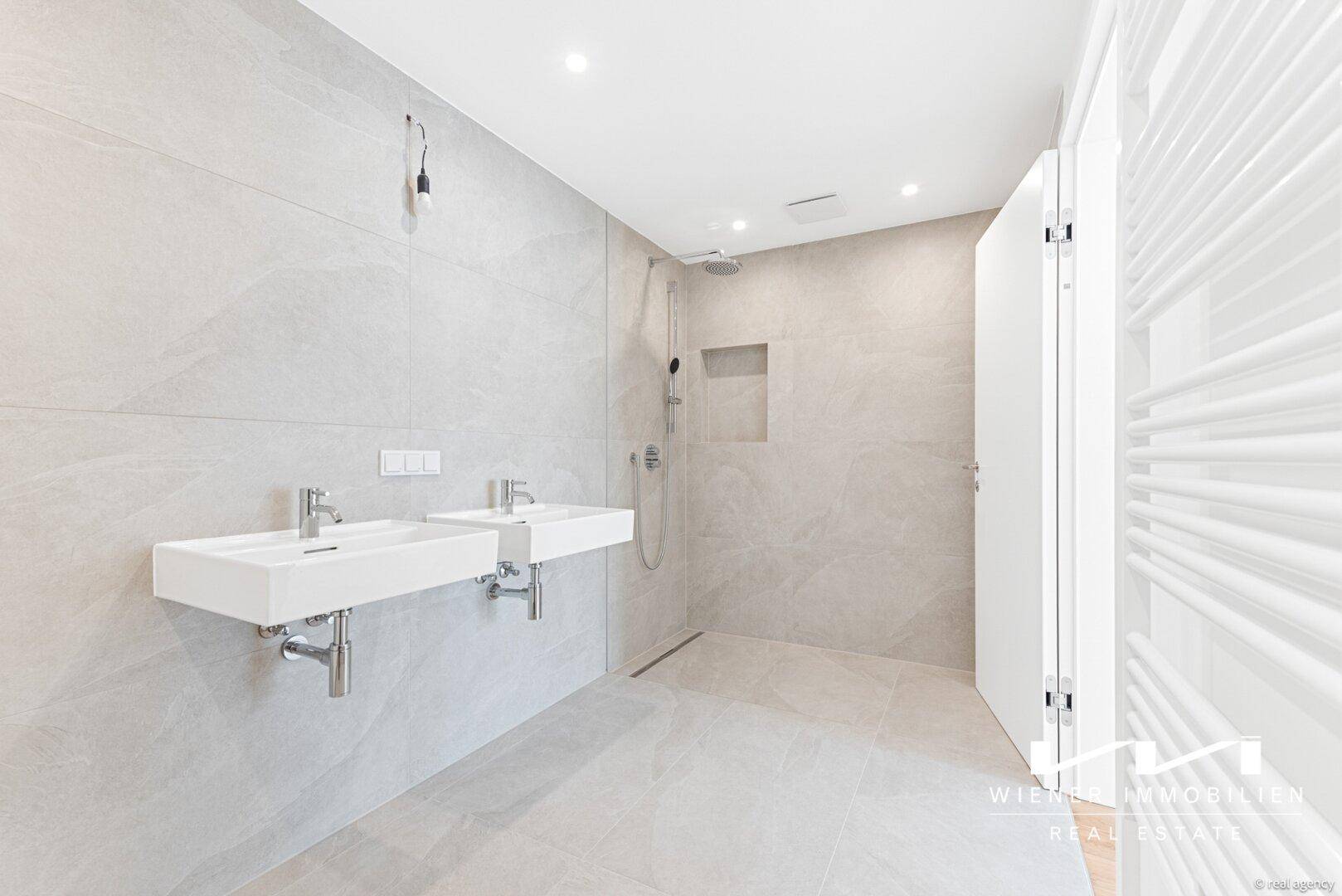 Modernes Badezimmer mit Doppelwaschbecken, ebenerdiger Dusche und beheiztem Handtuchhalter.