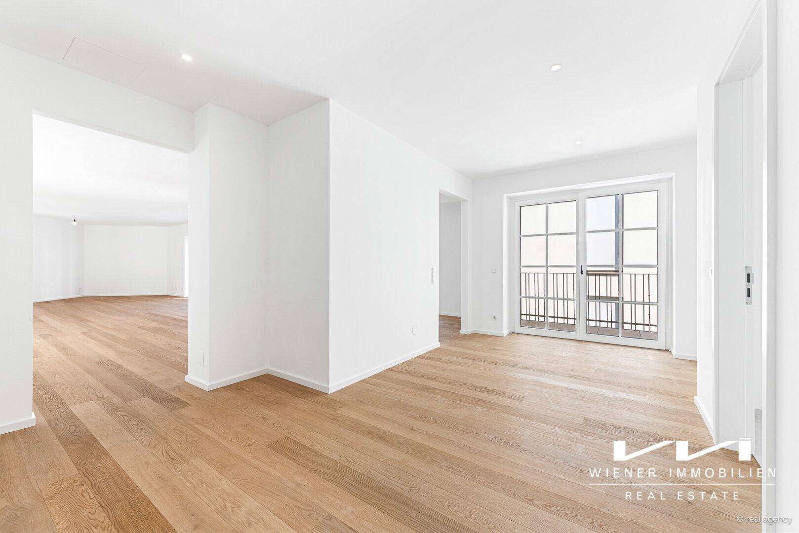 Heller Wohnbereich mit Eichenparkett und Zugang zu einem französischen Balkon, ideal für offenes Wohnen.