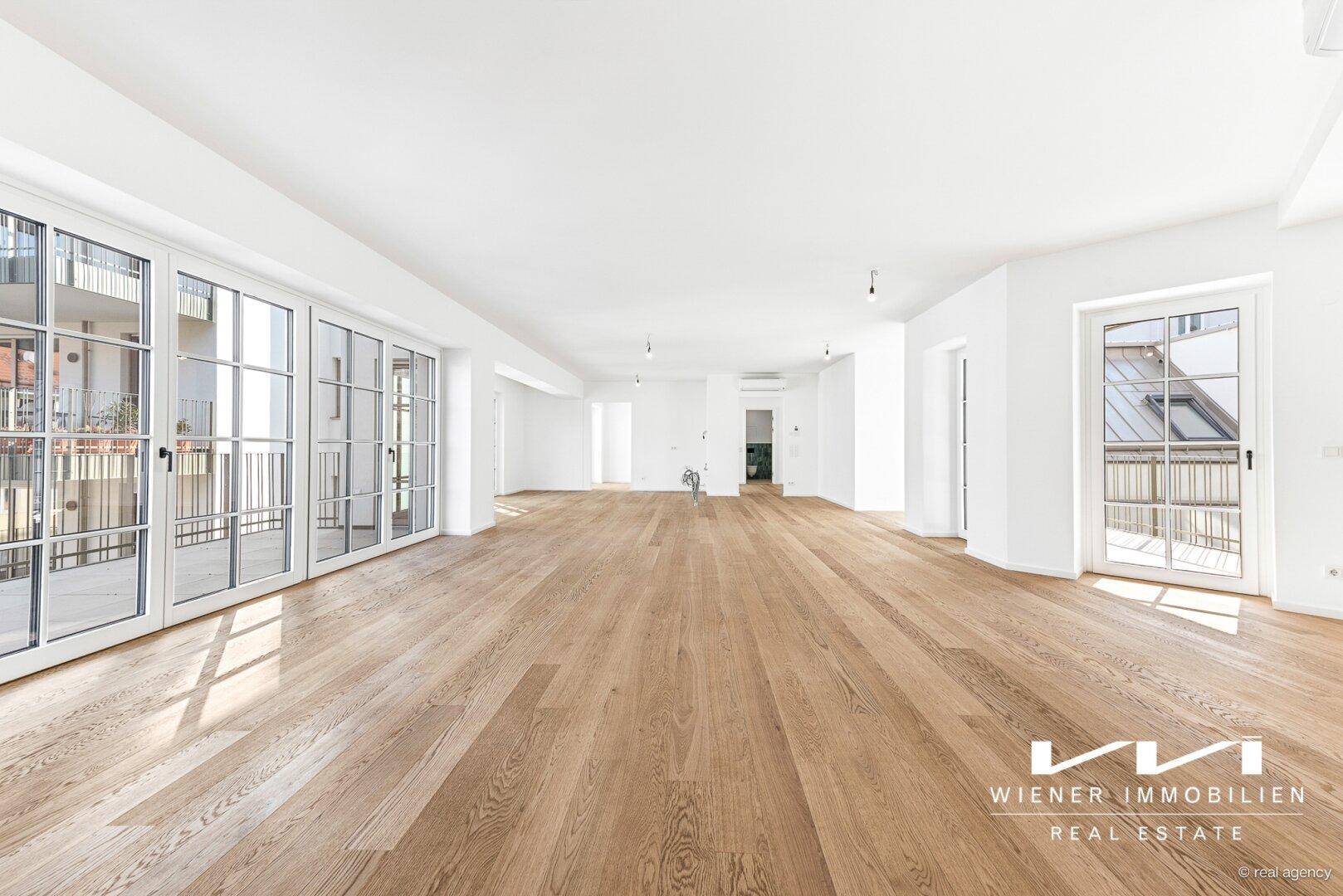 Großzügiger, lichtdurchfluteter Wohnbereich mit Eichenparkett und mehreren Balkonzugängen.