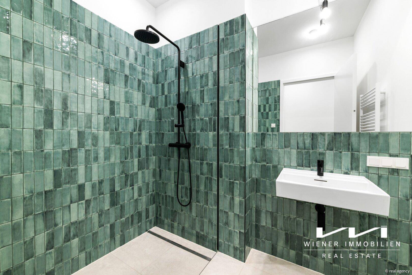 Modernes Badezimmer mit grünen Fliesen, einer begehbaren Dusche und minimalistischem Waschbecken.