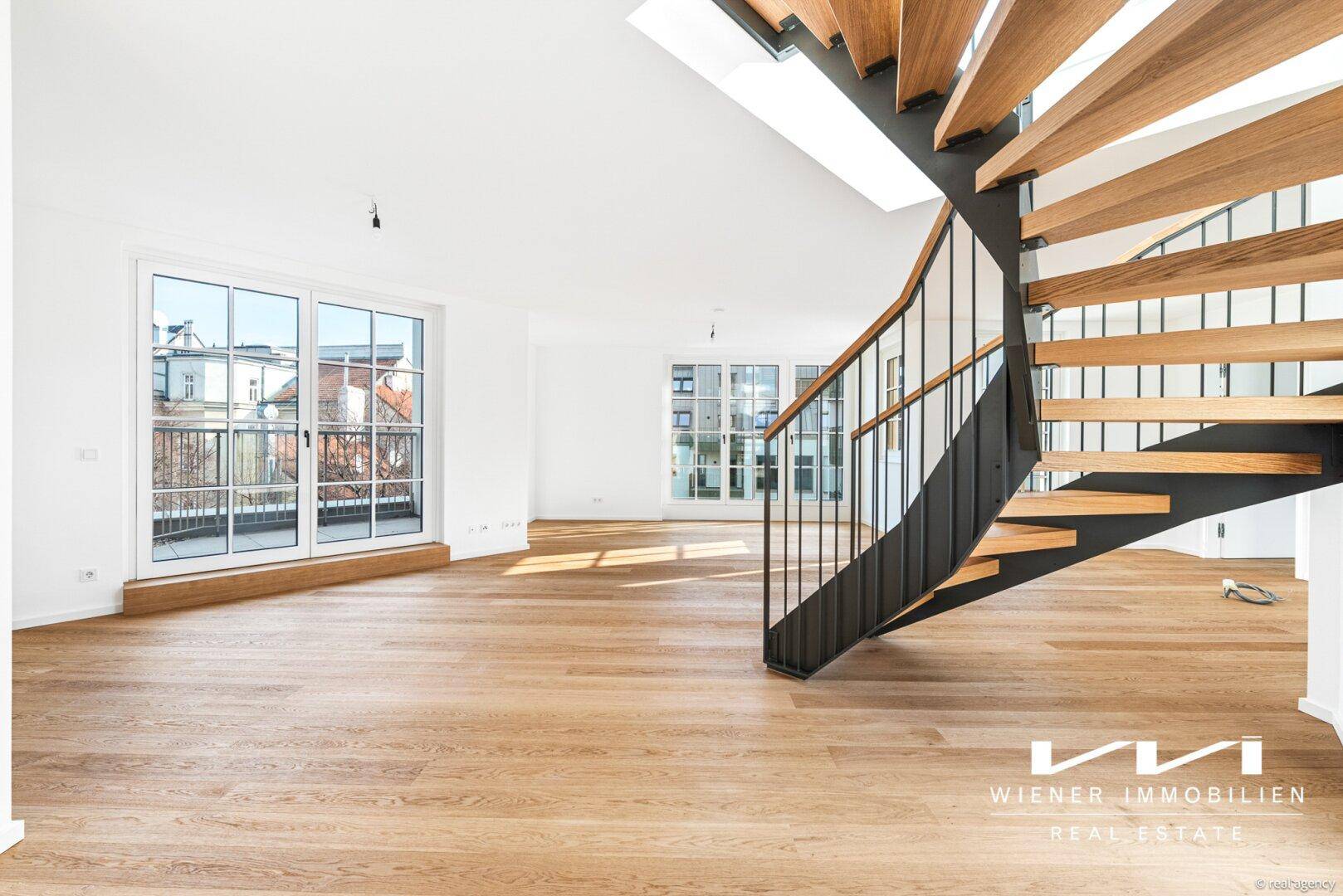 Heller Wohnbereich mit Holzparkett, großen Fenstern und einer eleganten Wendeltreppe, die nach oben führt.
