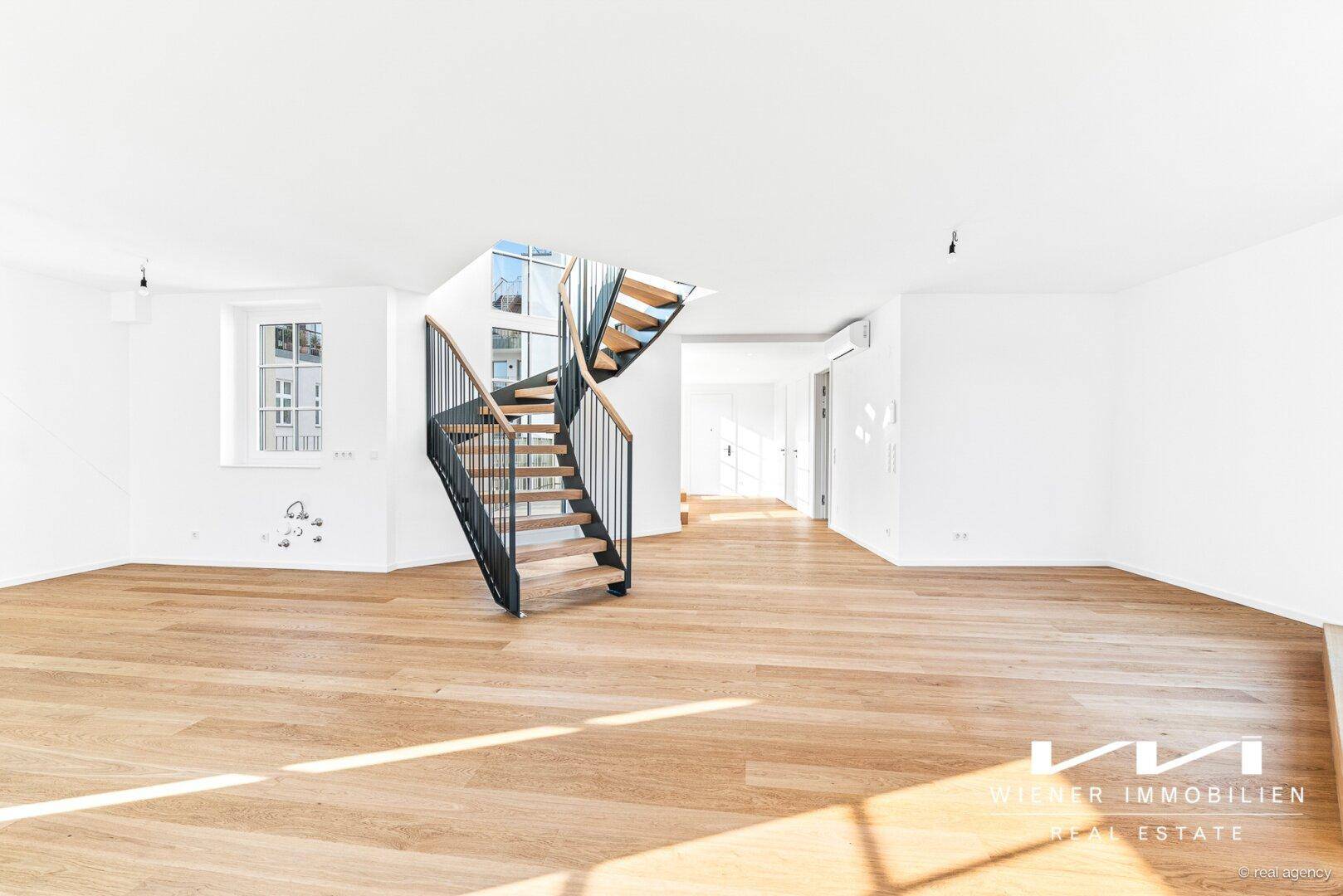 Geräumiger, heller Wohnbereich mit Holzparkettboden, großen Fenstern und einer modernen Wendeltreppe.