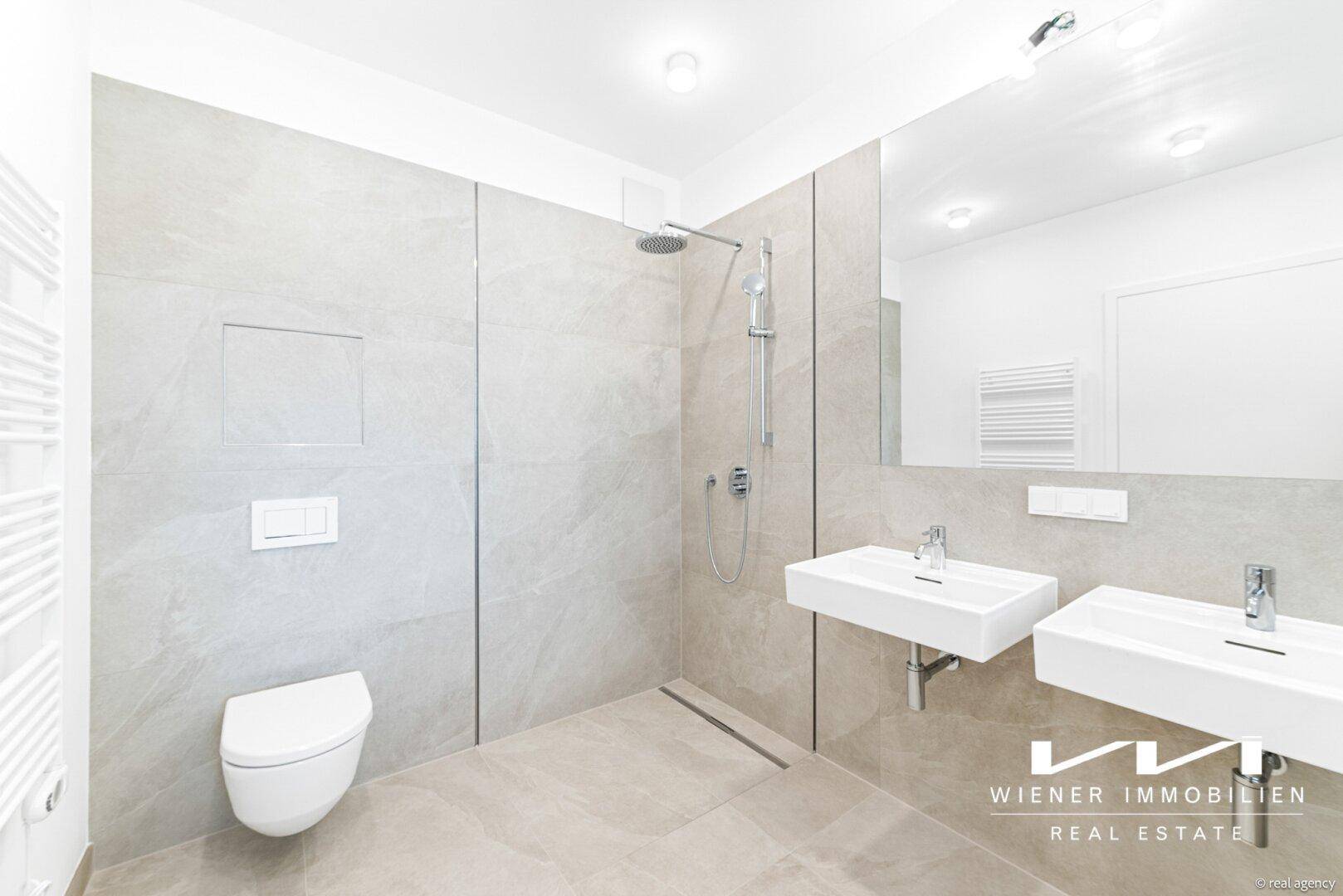 Modernes Badezimmer mit ebenerdiger Dusche, Doppelwaschbecken und Wand-WC in hellen Grautönen.