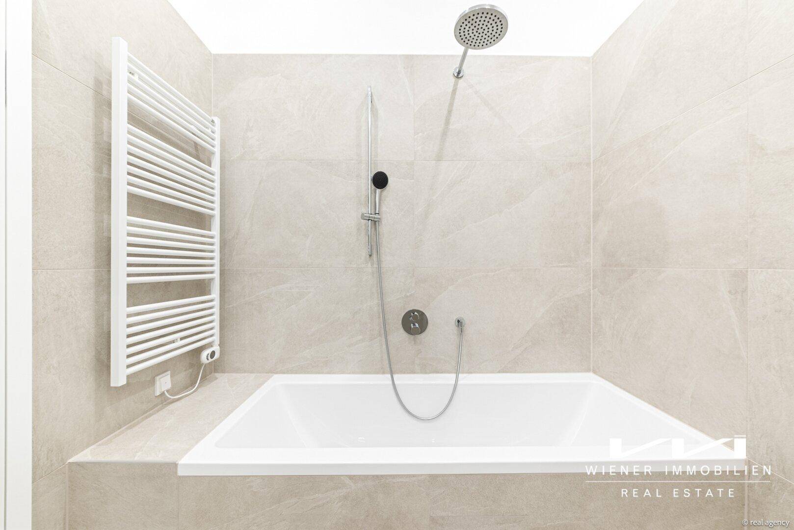 Modernes Badezimmer mit Badewanne, Duschfunktion und praktischem beheiztem Handtuchhalter an der Wand.
